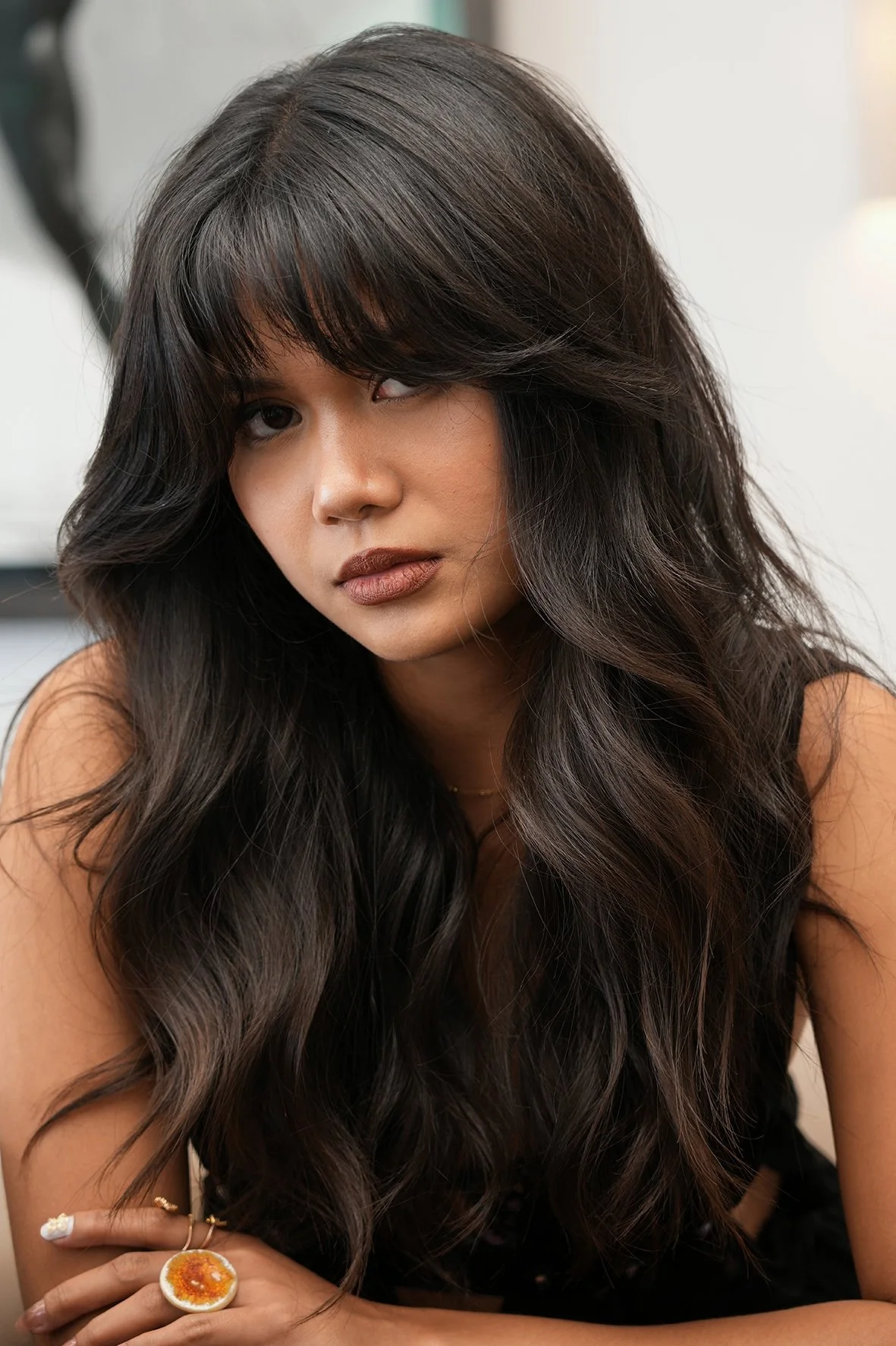 A woman with long, dark, rich colour wavy hair, styled by Elle Bondoc.