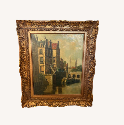 Painting of a cityscape with historic buildings and water, framed in an ornate gold frame.