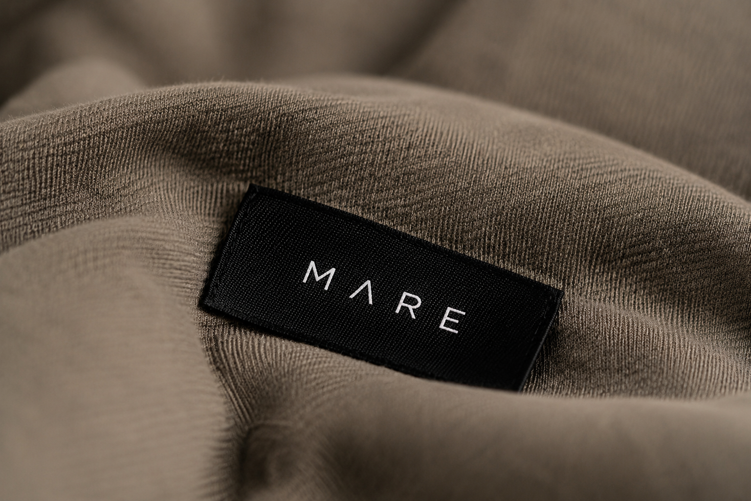 Close-up of a clothing label with the brand name 'MARE' sewn onto a beige fabric garment.
