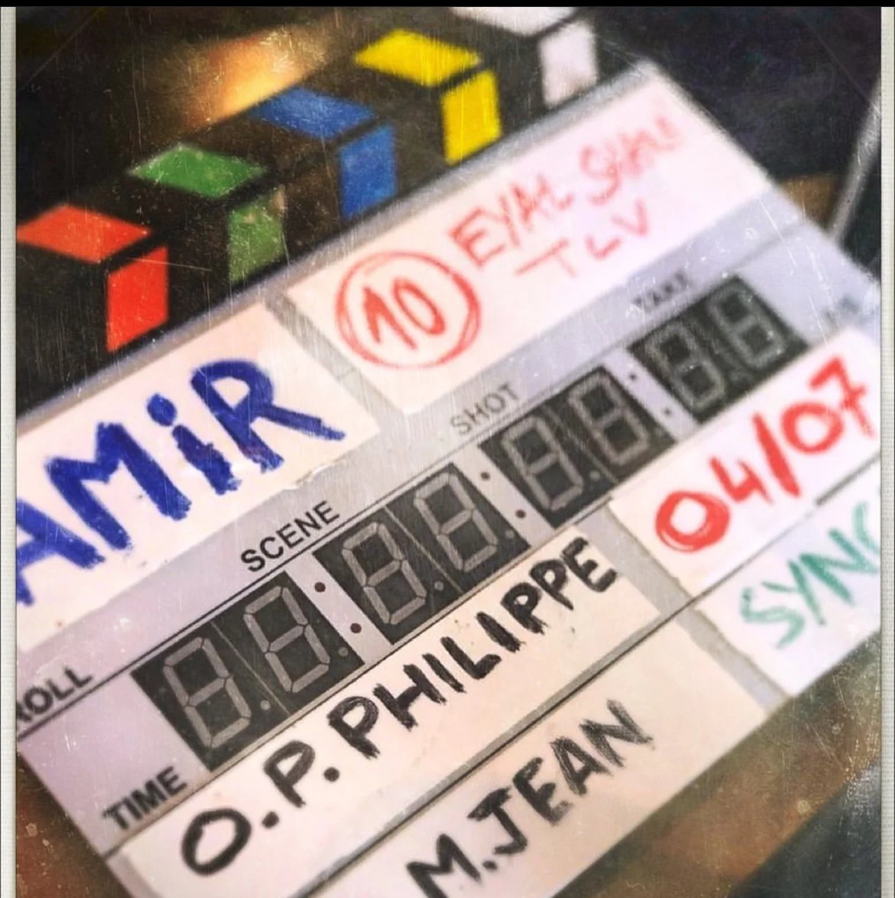 Clapperboard with the word 'MIR' in blue, and handwritten notes with red and green marker. It is used in film production to mark scenes and takes.