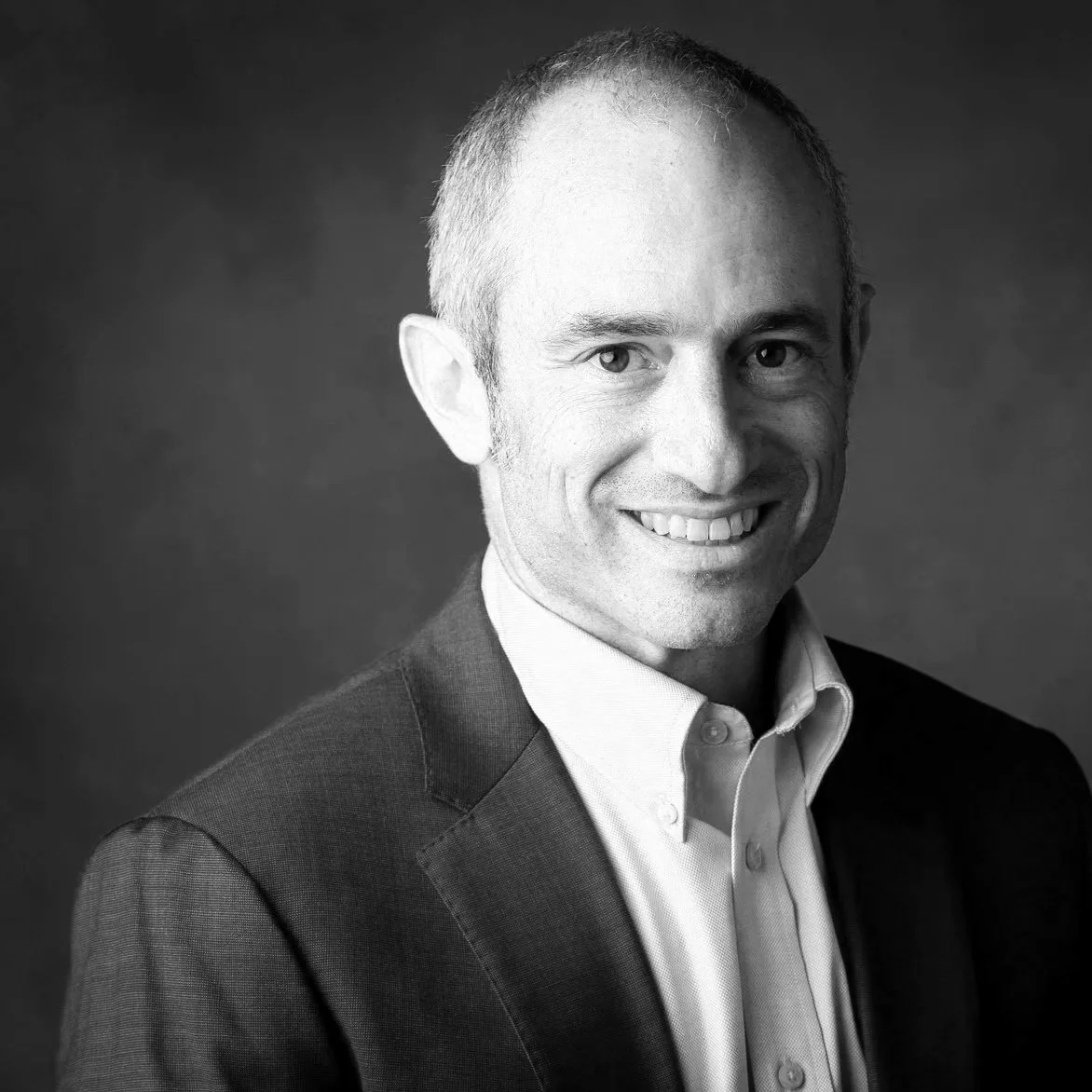 Black and white photo of Noah Nuer. He is wearing a suit and collared shirt.