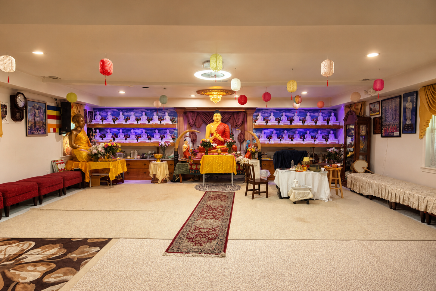 Interior of a Buddhist temple decorated with statues of the Buddha, flowers, and colorful lanterns hanging from the ceiling.