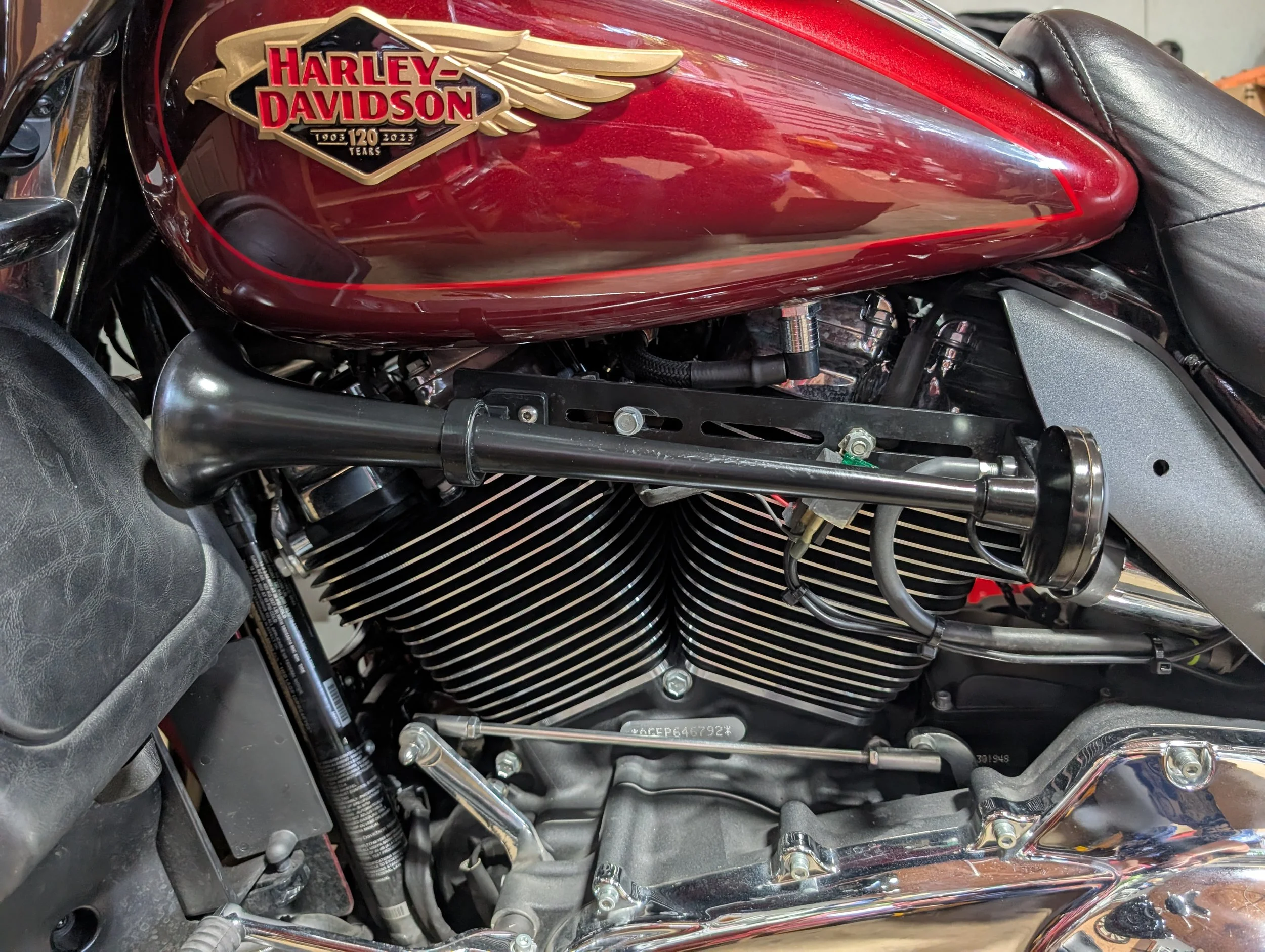 Harley Davidson logo emblem on a red motorcycle gas tank, indicating 120 years from 1903 to 2023.