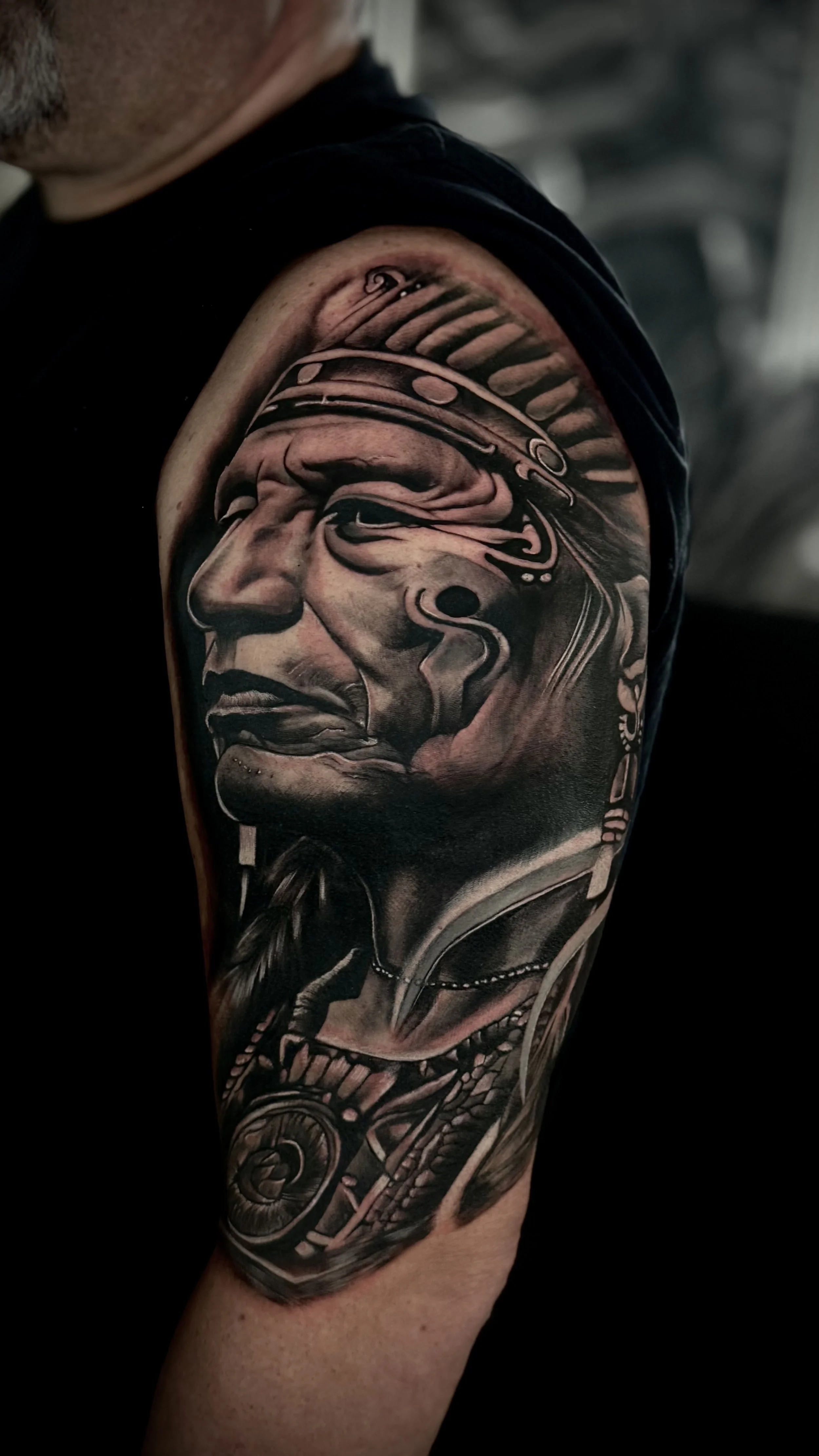 Tattoo eines indianischen Kriegers, der eine Feder im Haar trägt, auf dem Oberarm eines Mannes.