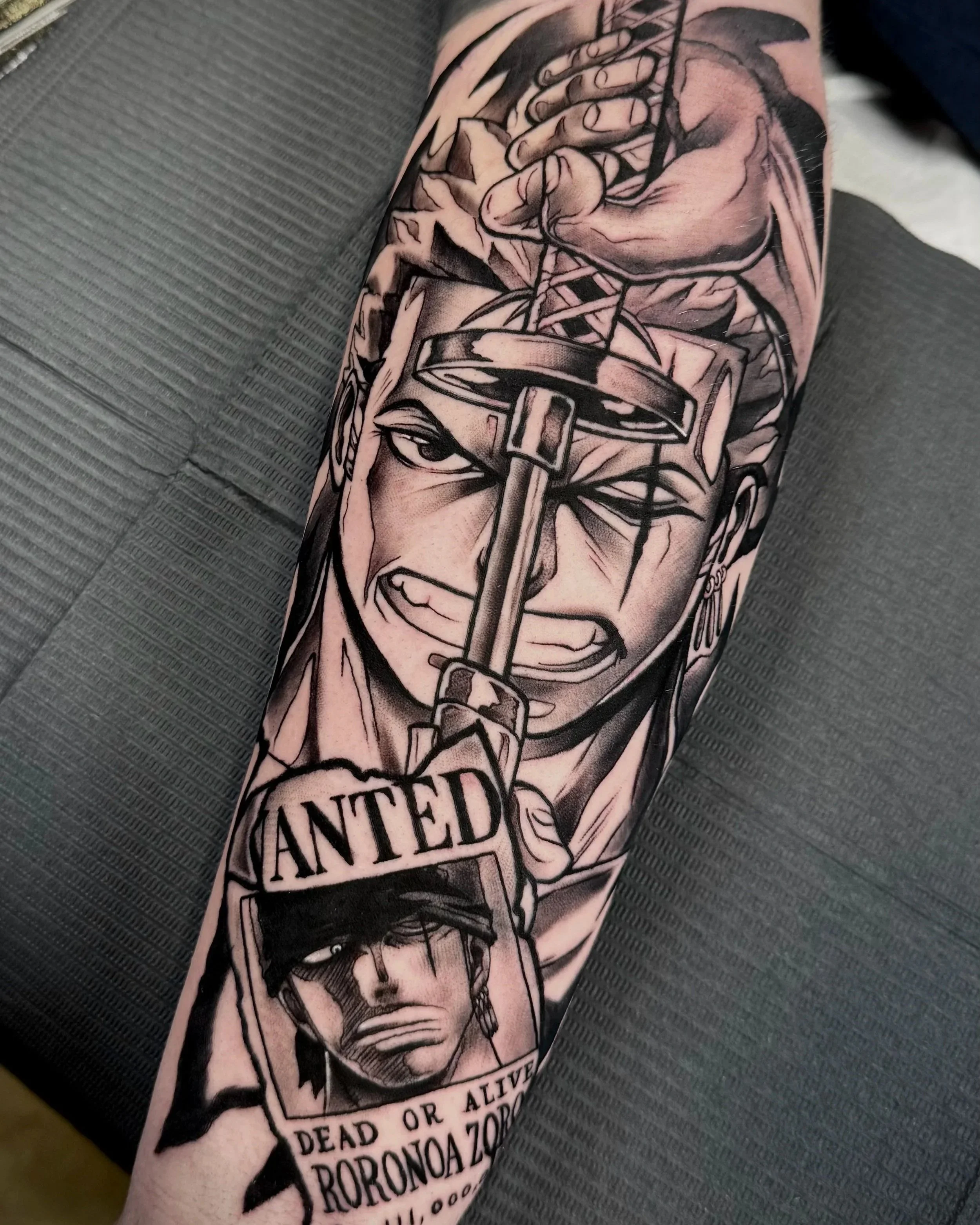 Schwarze und graue Tätowierung eines Mannes, der einen Hammer hält, mit Text auf dem unteren Teil des Tattoos, das Worte wie 'Atemlos oder lebendig', 'Tot oder lebendig', 'Tod oder leben' und 'Donora' enthält.