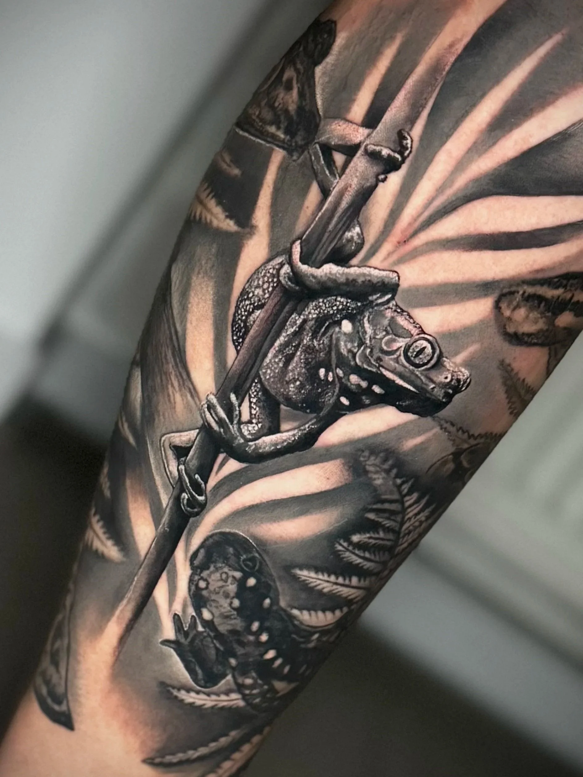 Schwarz-weiße Tätowierung eines Straußes auf einem Arm.