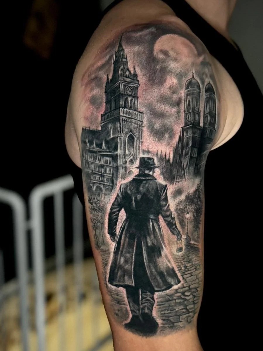 Realistische Black-and-Grey Tätowierung mit Sherlock Holmes und der Skyline von München auf dem Oberarm.