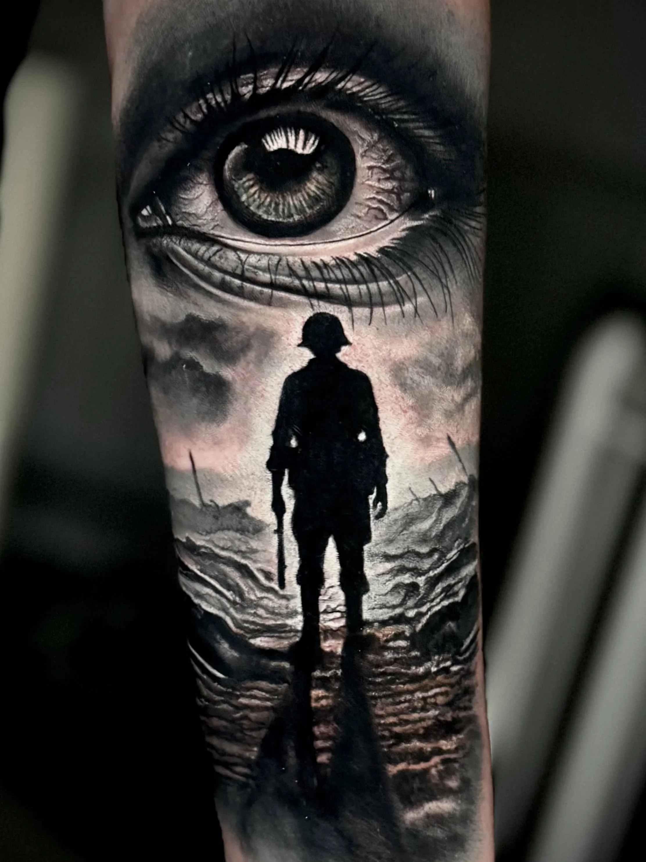 Realistische Black-and-Grey Tätowierung mit Auge und Soldaten-Silhouette, inspiriert vom Albumcover von Metallica, auf dem Unterarm.