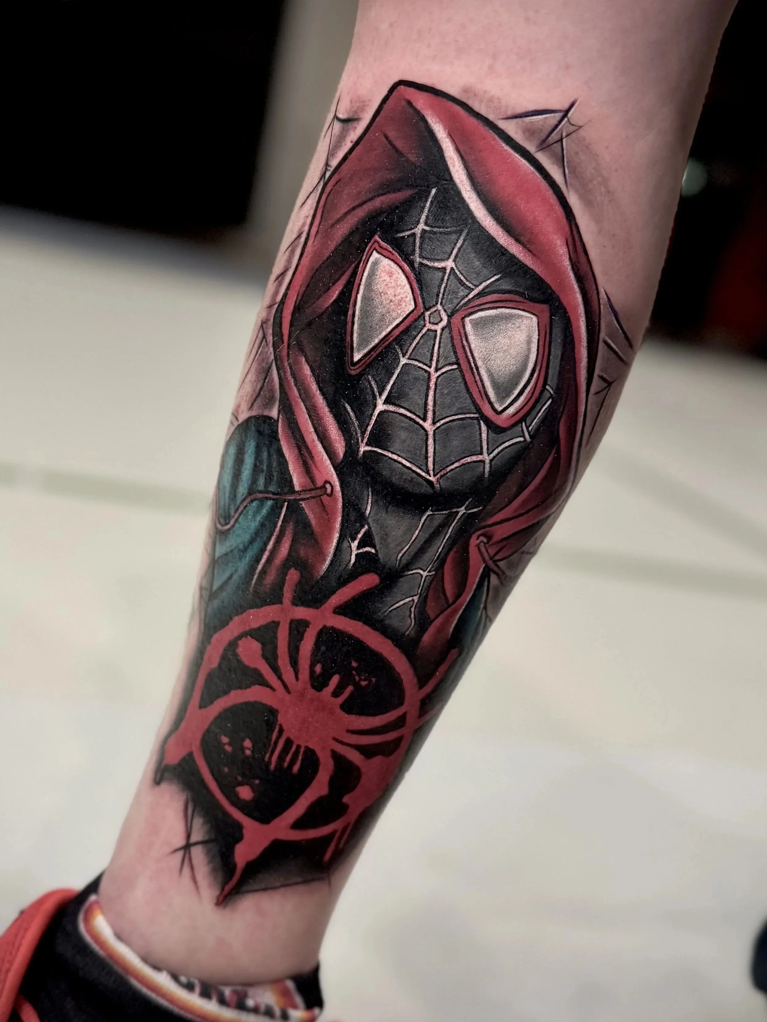 Farbige Miles Morales Spider-Man Tätowierung im Comic-Stil auf der Wade. 
