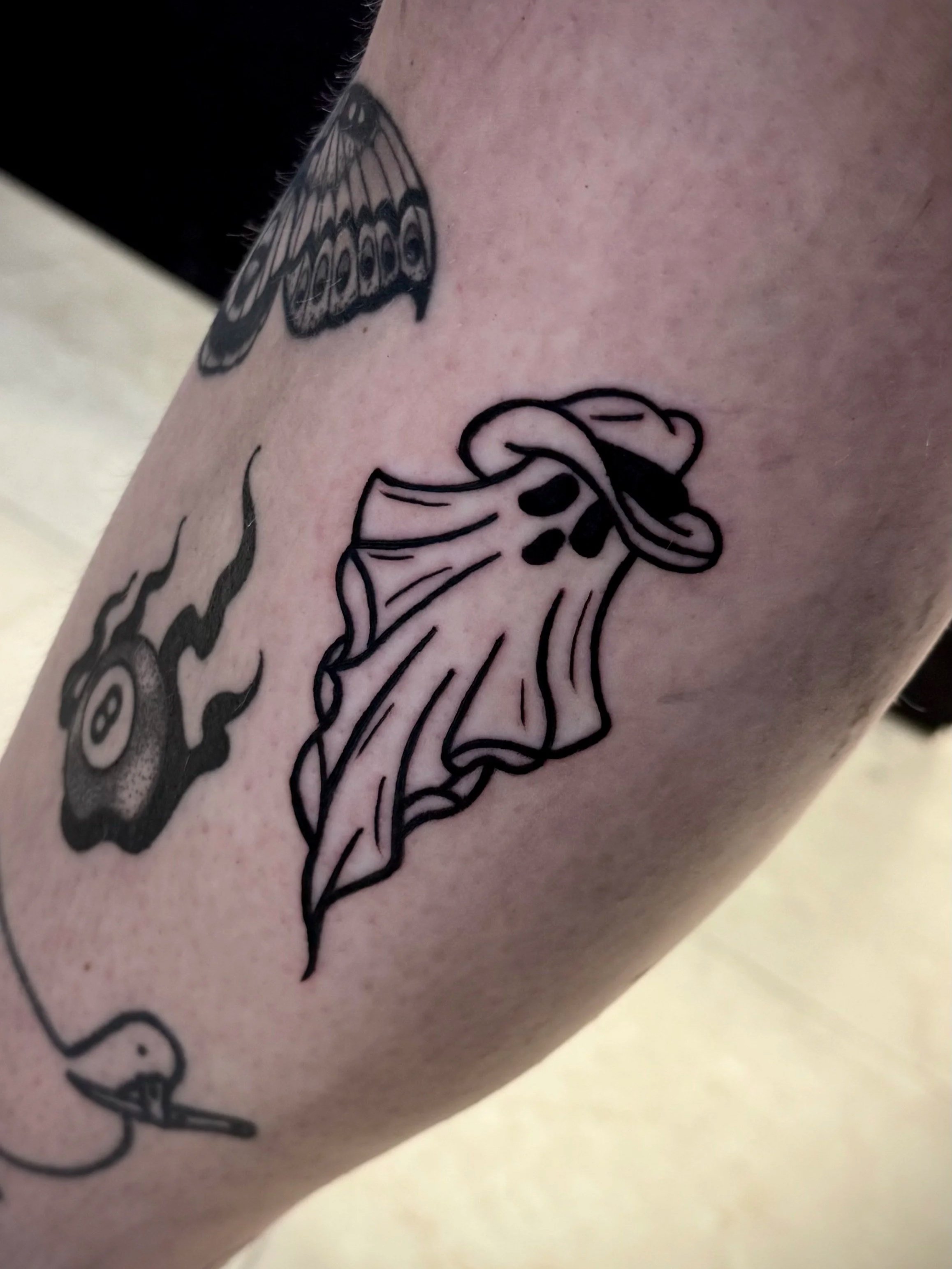Tattoo eines Schmetterlings auf der Haut, teilweise sichtbar, in Schwarz umrandet.