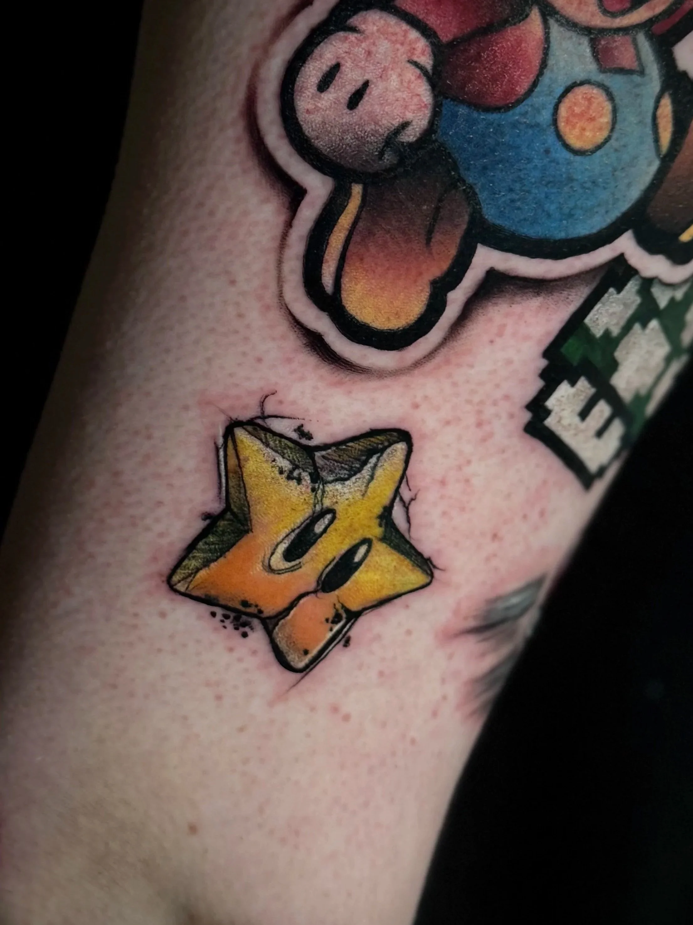 Tattoo eines Kühchens mit einem lachenden Gesicht, blauer Jacke und gelbem Schal auf der Haut.