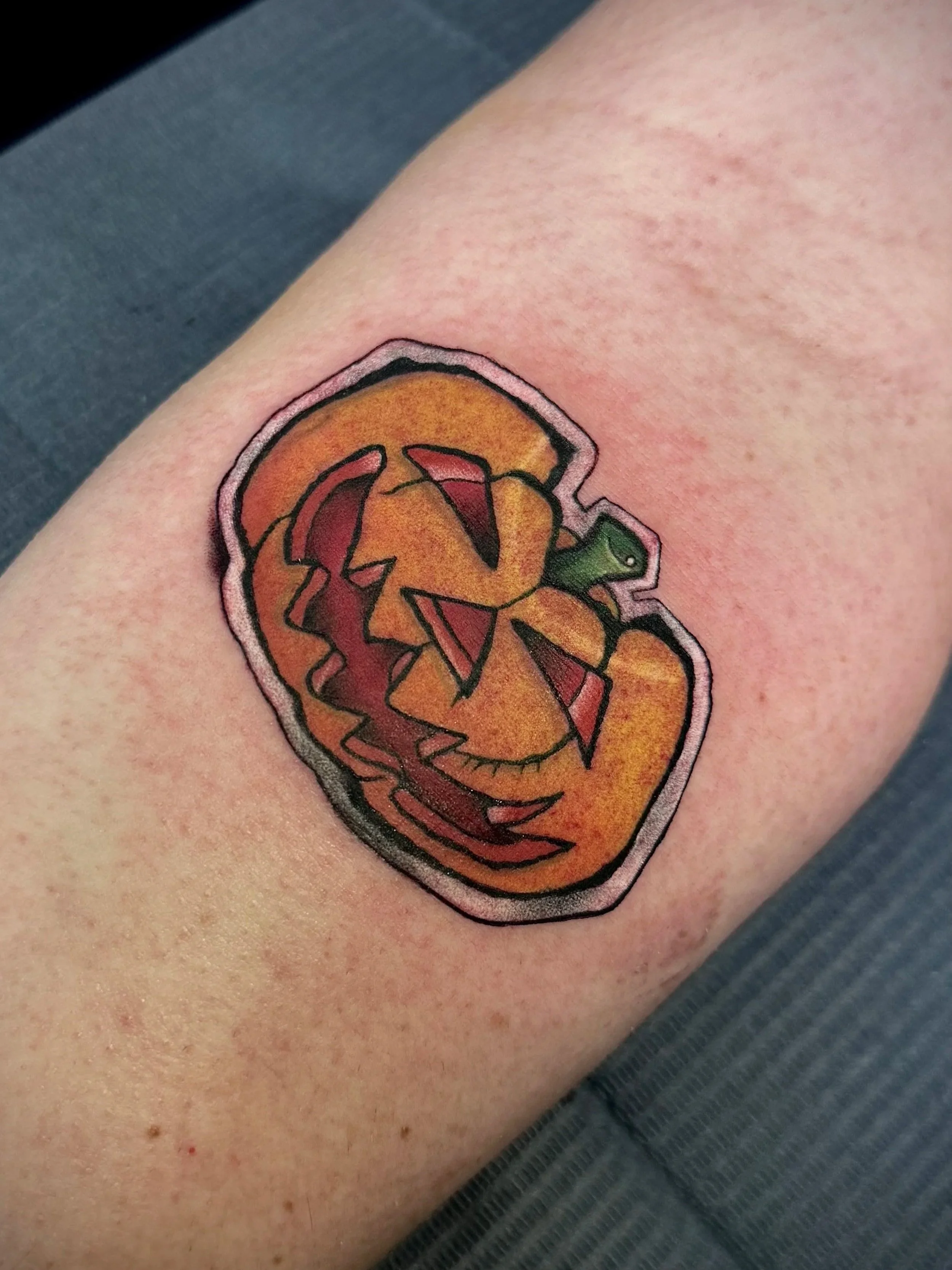 Tattoo eines Kürbisses mit Astronautenhelm auf der Haut.