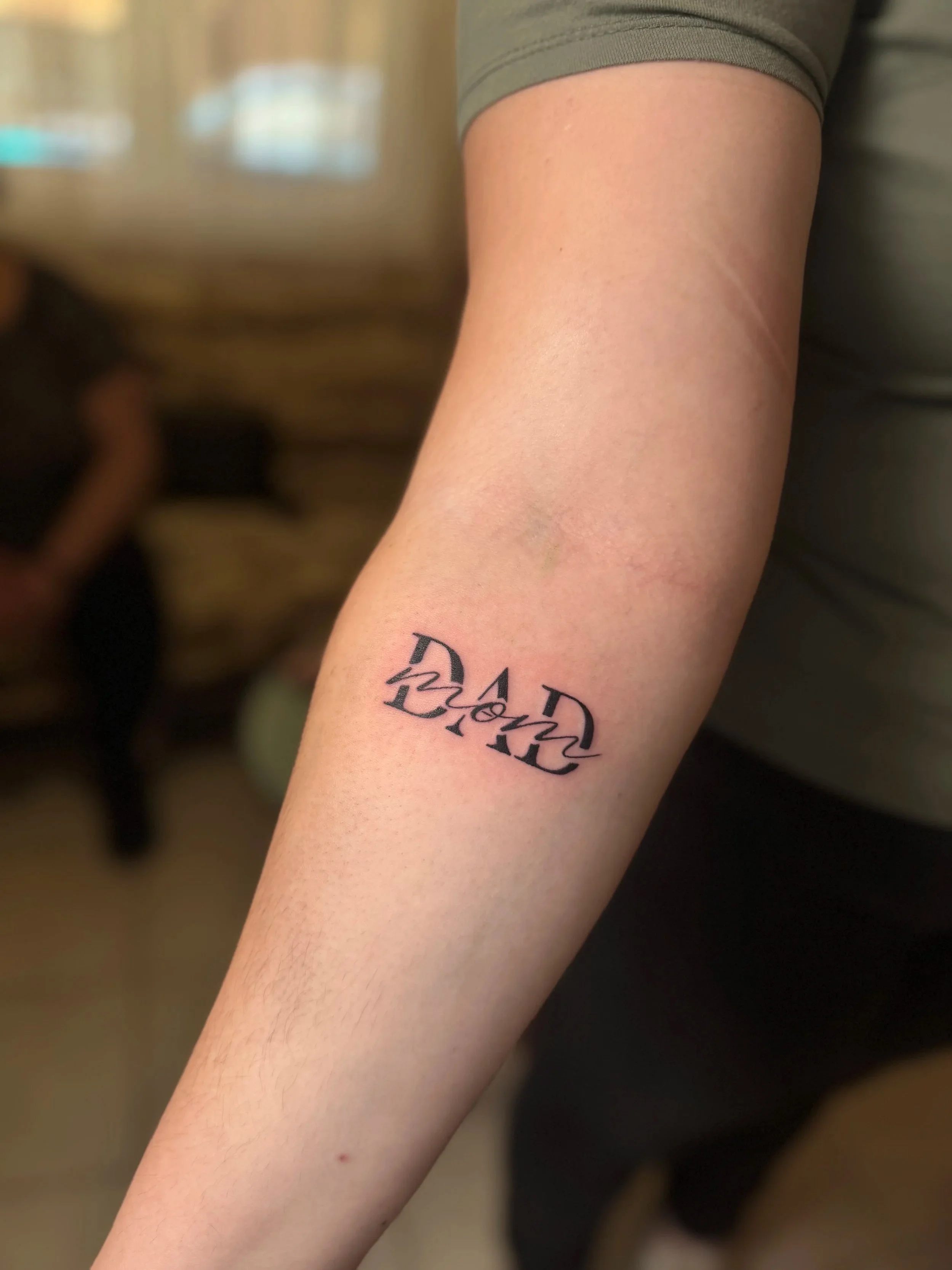 Naheaufnahme eines Arms mit einem Tattoo, das den Text 'D23A' und eine smiley-ähnliche Figur zeigt.