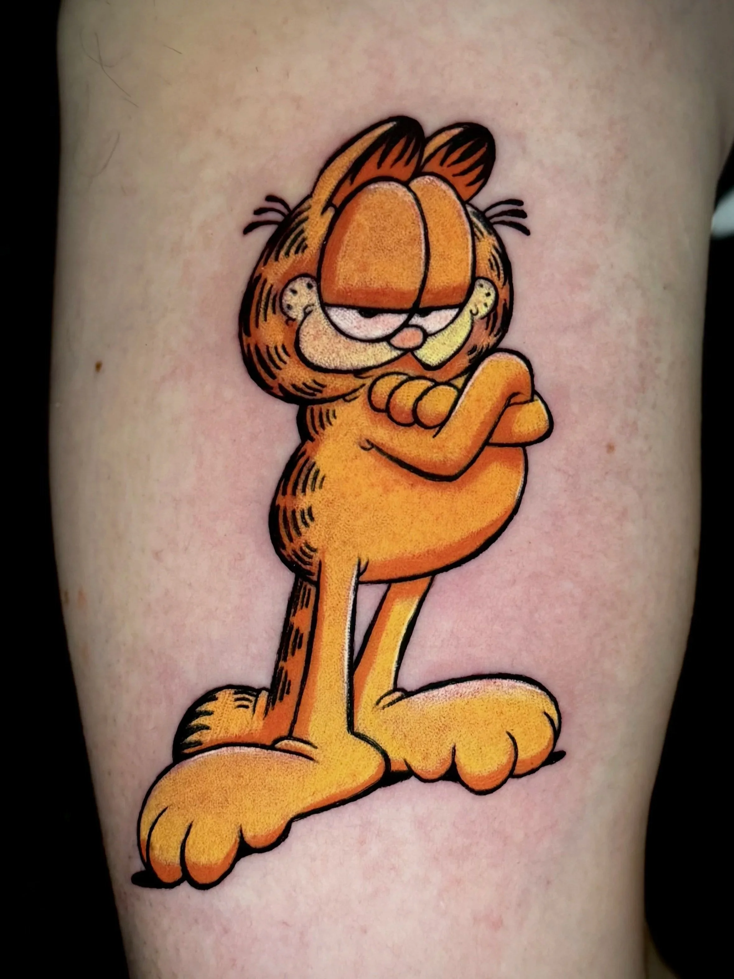 Tätowierung von Garfield, der cartoonhaften orangen Katze, die für ihre faulen und schlagfertigen Eigenschaften bekannt ist.