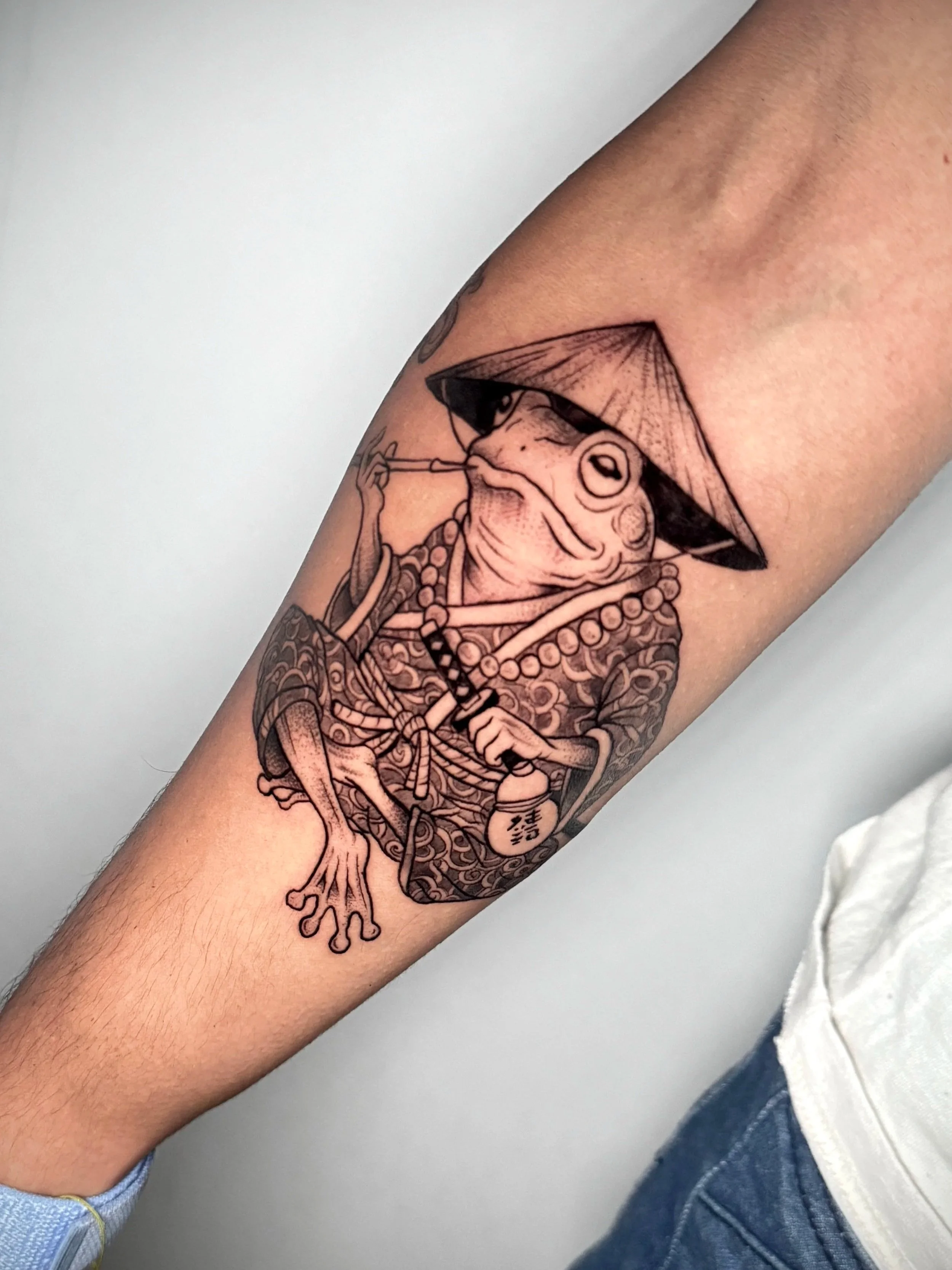 Tattoo eines Froschs mit Pfeil auf dem Arm