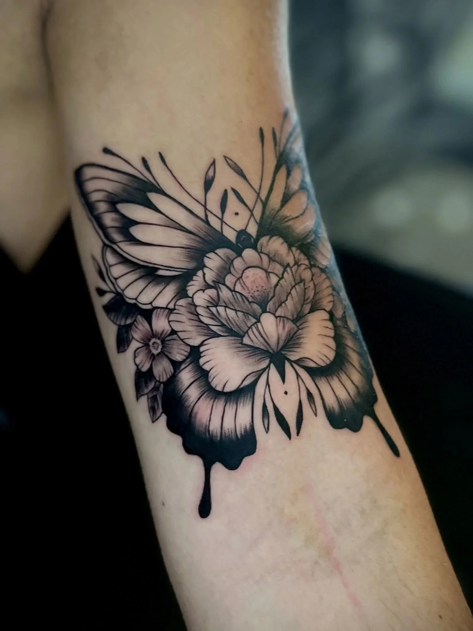 Schwarze und graue Tätowierung eines Schmetterlings auf einem Arm