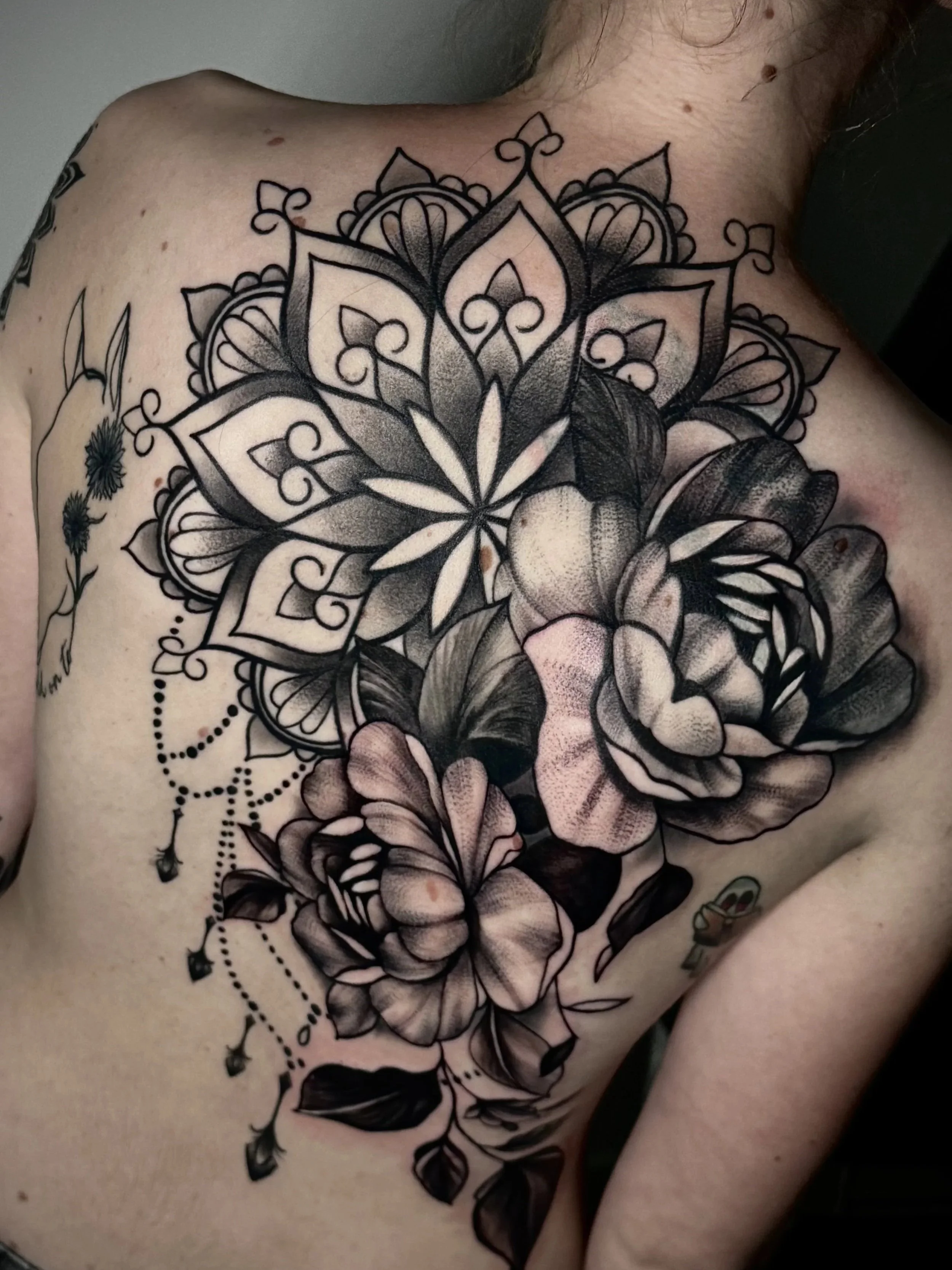 Detailliertes schwarzes Mandala-Tattoo auf der Schulter und Brust eines Menschen.