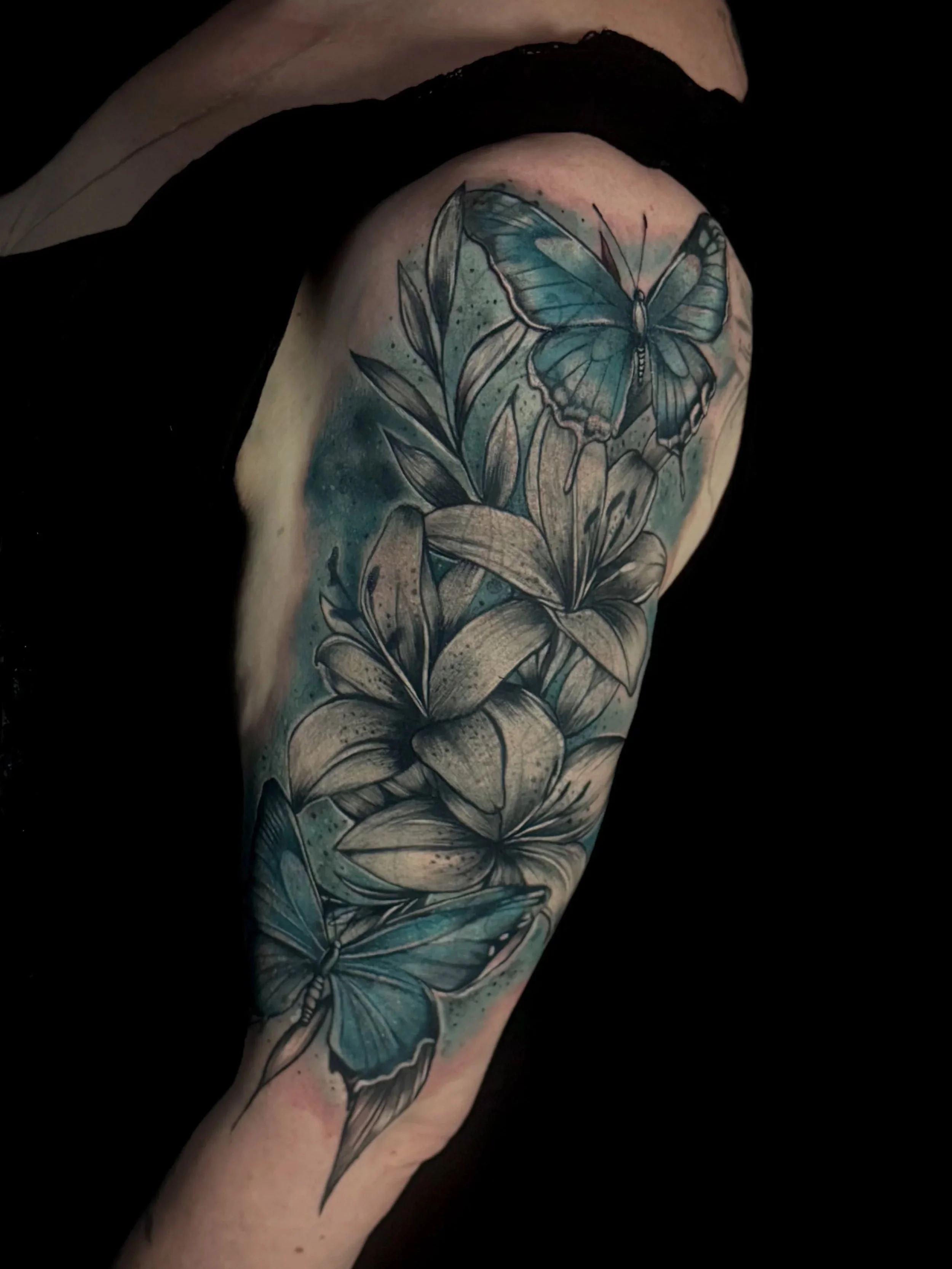 Tattoo eines blauen Schmetterlings auf dem Oberarm