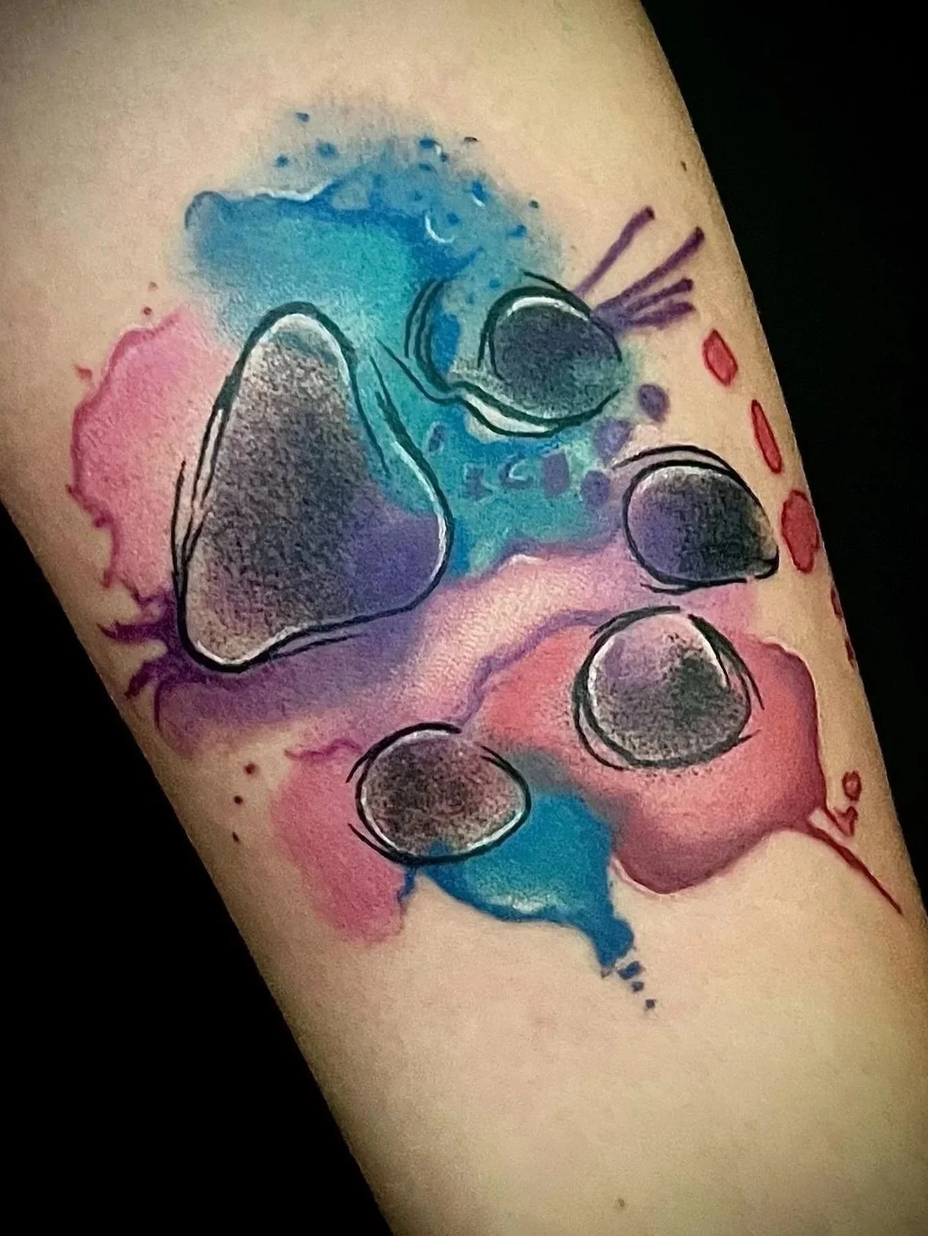 Bunte Tätowierung eines Pandabären auf der Haut, mit Wasserfarbenähnlichen Effekten in Blau, Pink, und Schwarz.