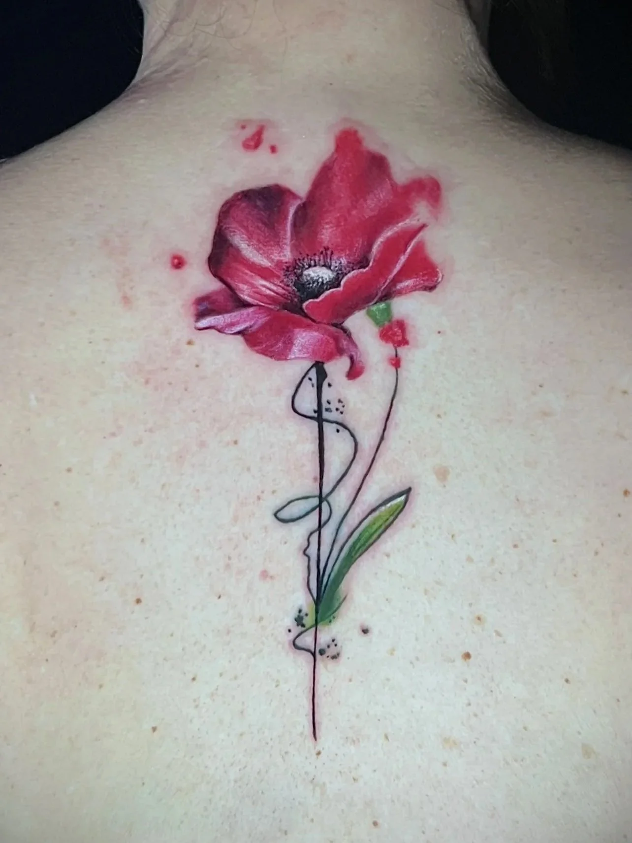 Tattoo einer roten Mohnblume mit grüner Blätter am Hals des Menschen.