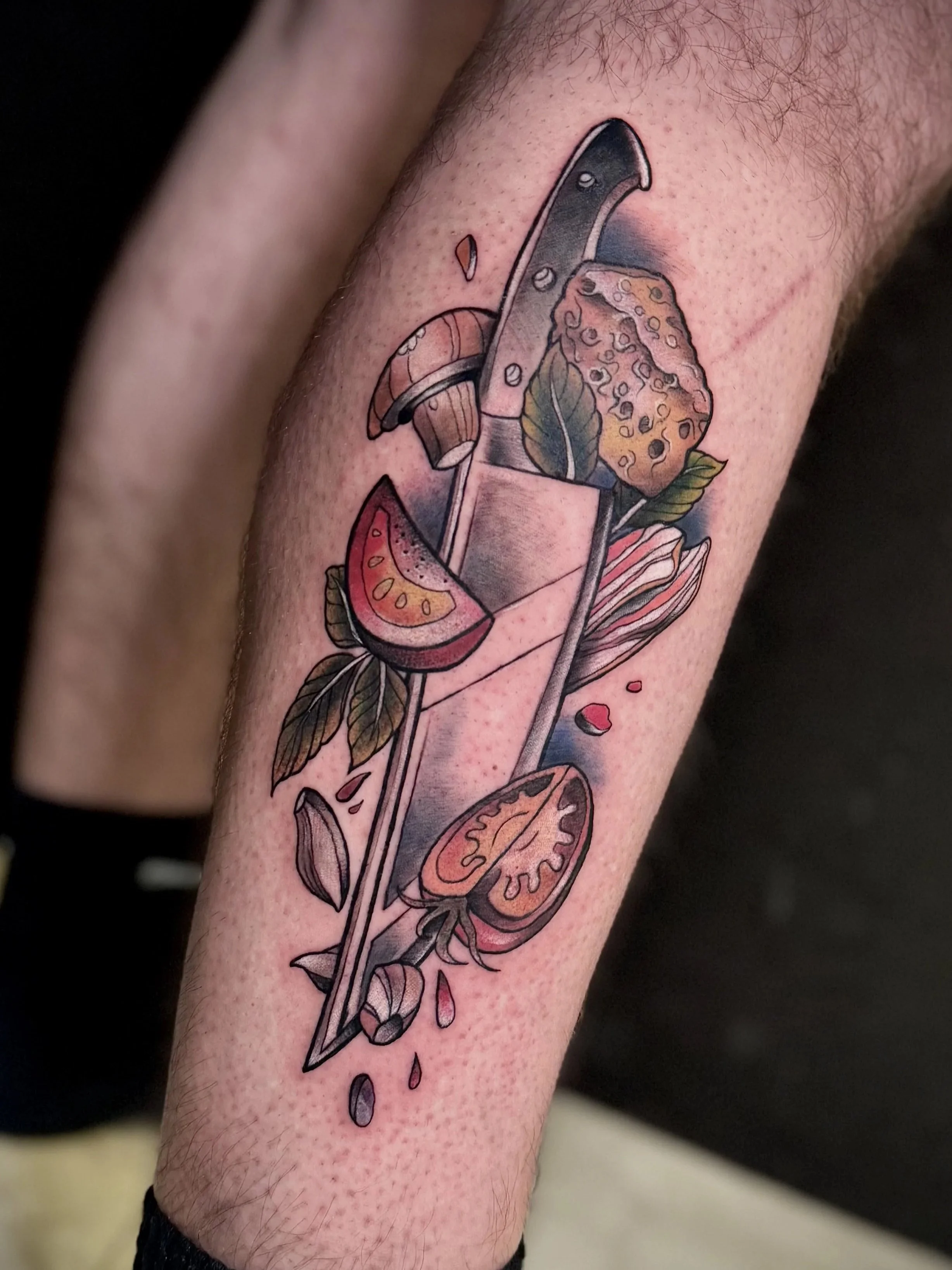 Superman-Stein mit einer Klinge, umgeben von Früchten, Beeren und Blättern, in einem farbigen Tattoo auf einem Unterarm.