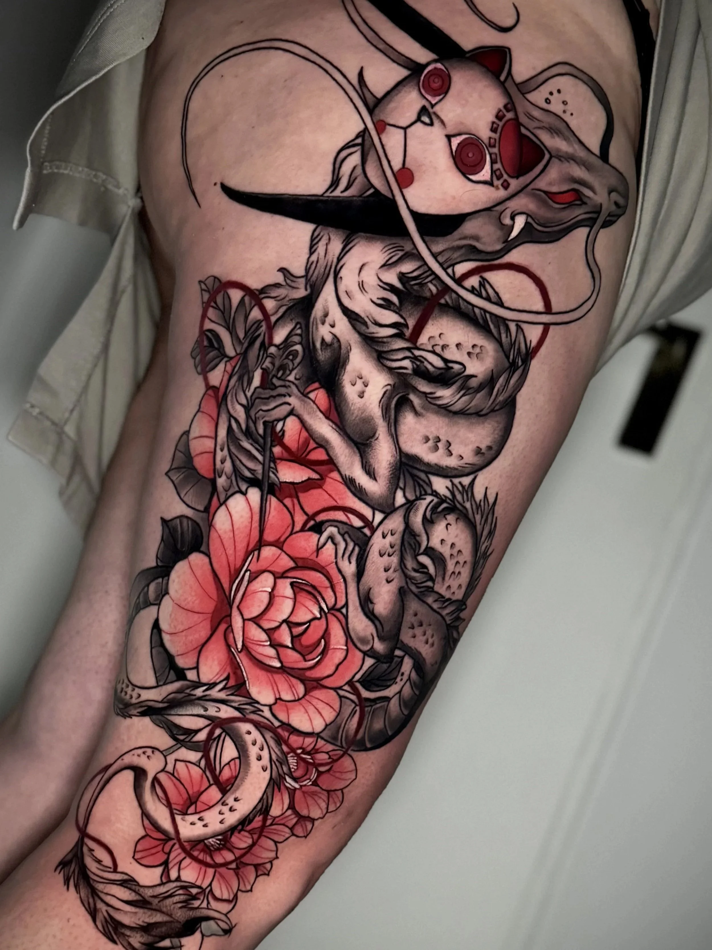 Hühnchen-Tattoo mit Rosen, Schlangen und anderen Symbolen auf einem menschlichen Arm.