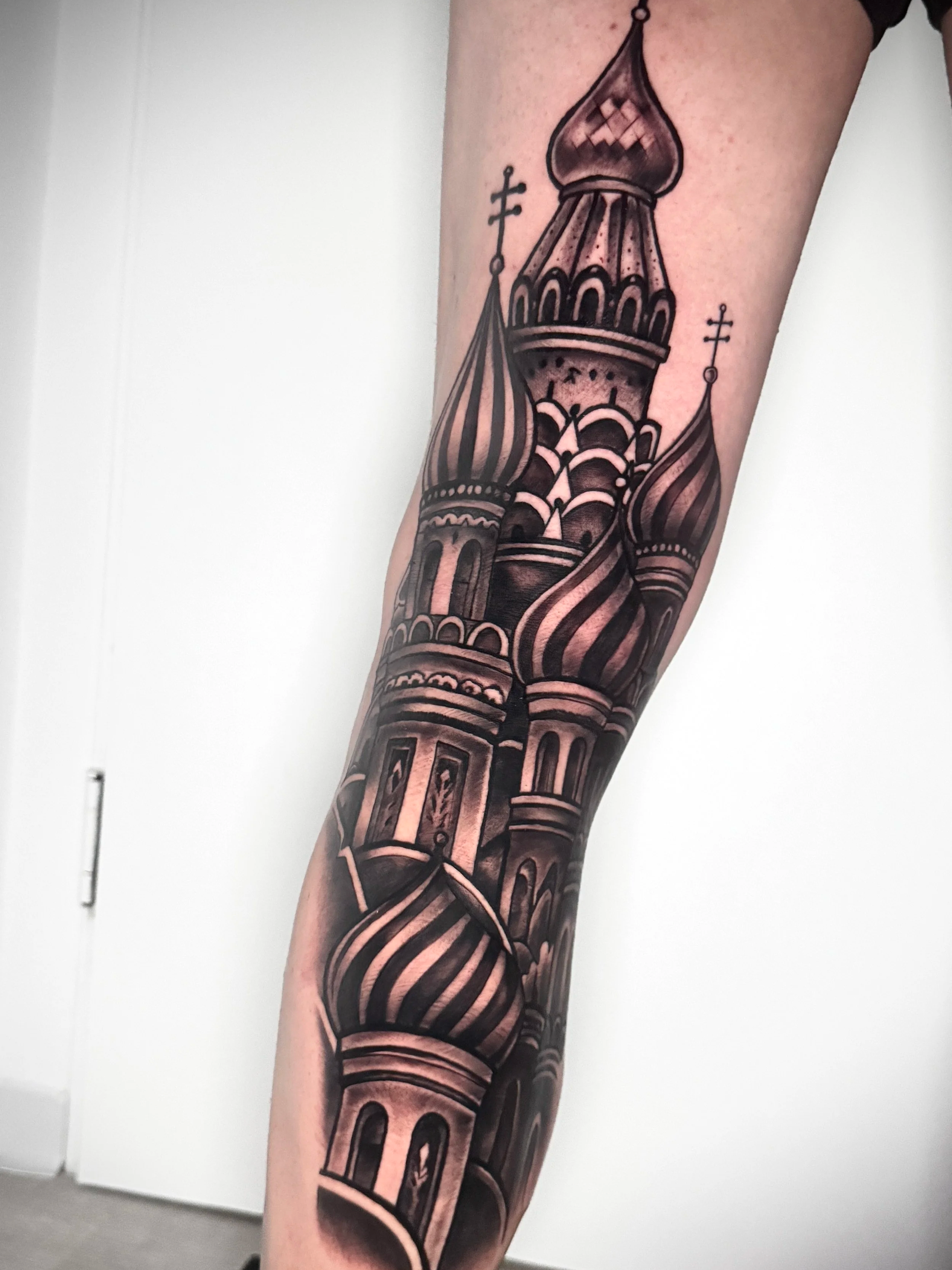 Schwarz-weiße Tattoo eines kubistischen Gebäudes mit Kuppeln auf einem Unterarm.
