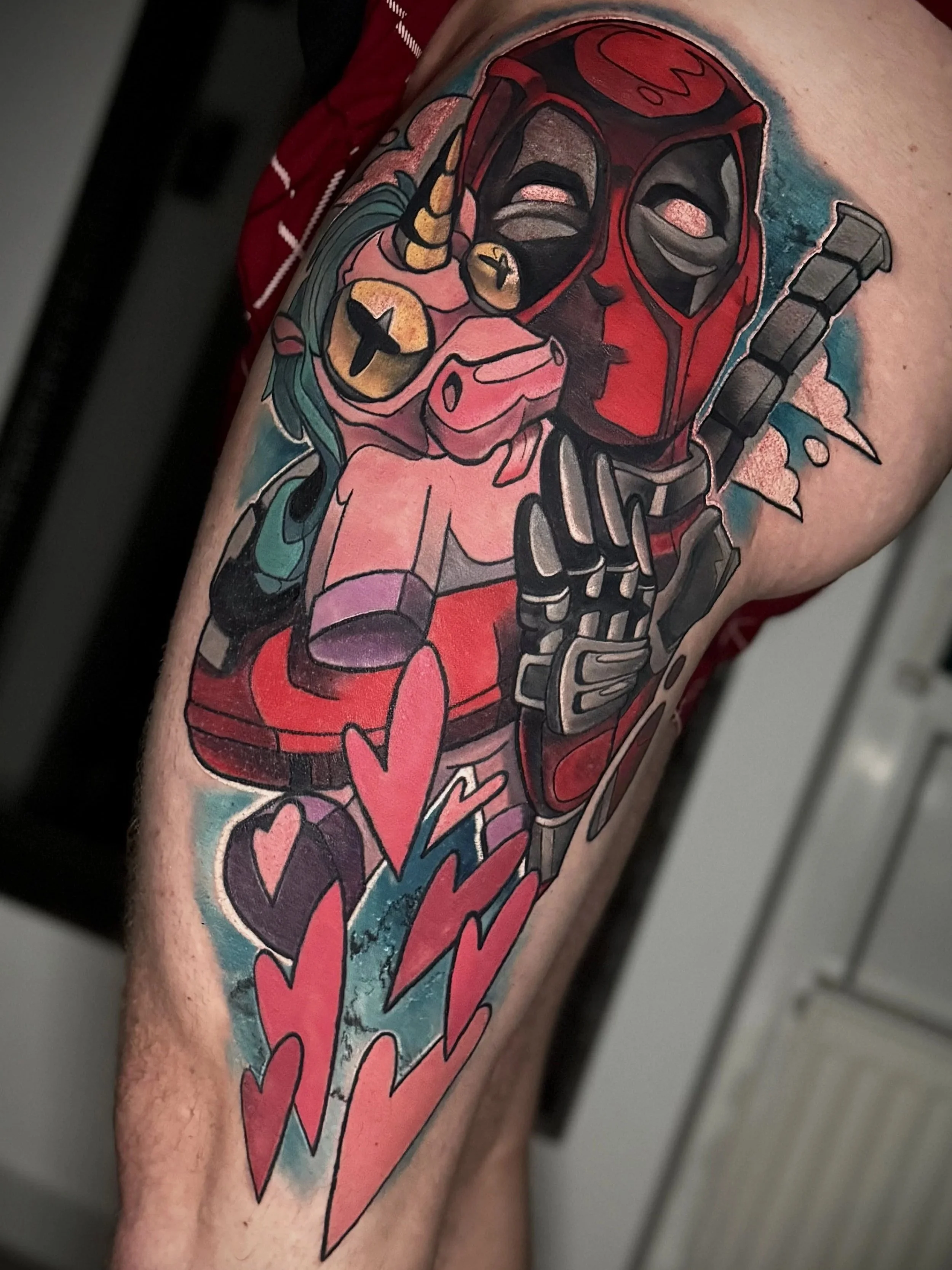 Eine bunte Tätowierung auf dem Unterarm mit einem roten Darth Vader Helm, einem Einhorn, einem Herz und verschiedenen Symbolen und Farben.