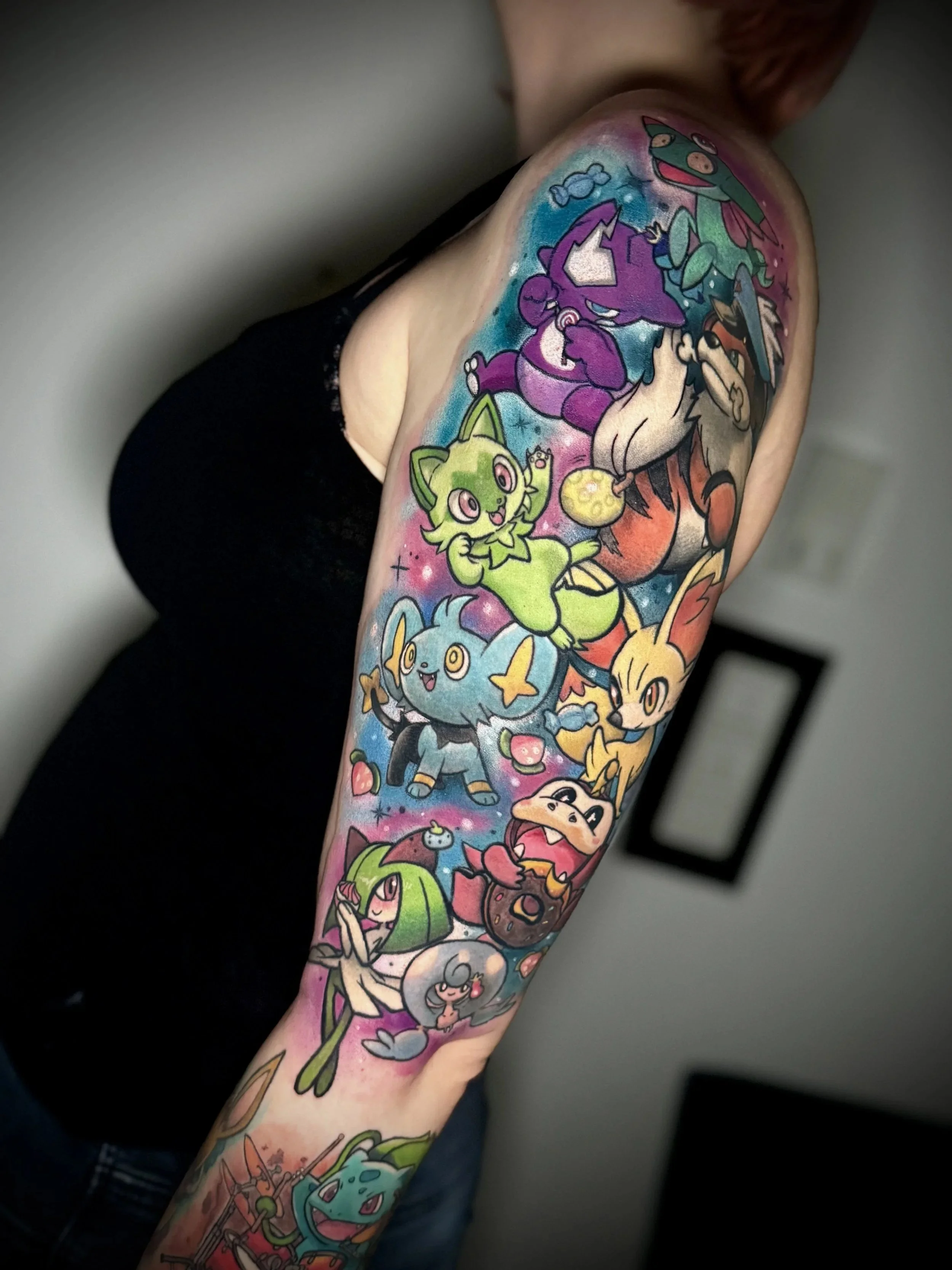 Eine farbenfrohe Tattoo-Tätowierung auf dem Arm, die verschiedene Pokémon-Charaktere darstellt.
