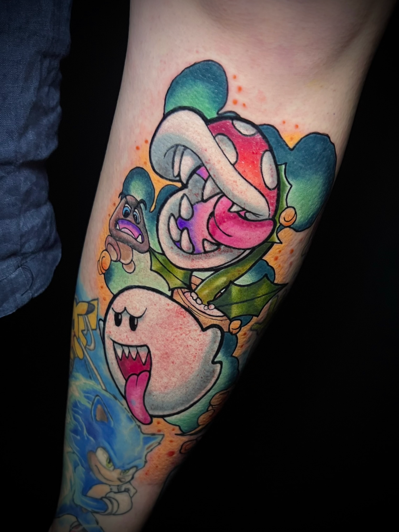 Tattoo von Super Mario Charakteren, darunter Toad mit rotem Hut, Bowsers Kopf und Bowser Jr. auf einem Arm.