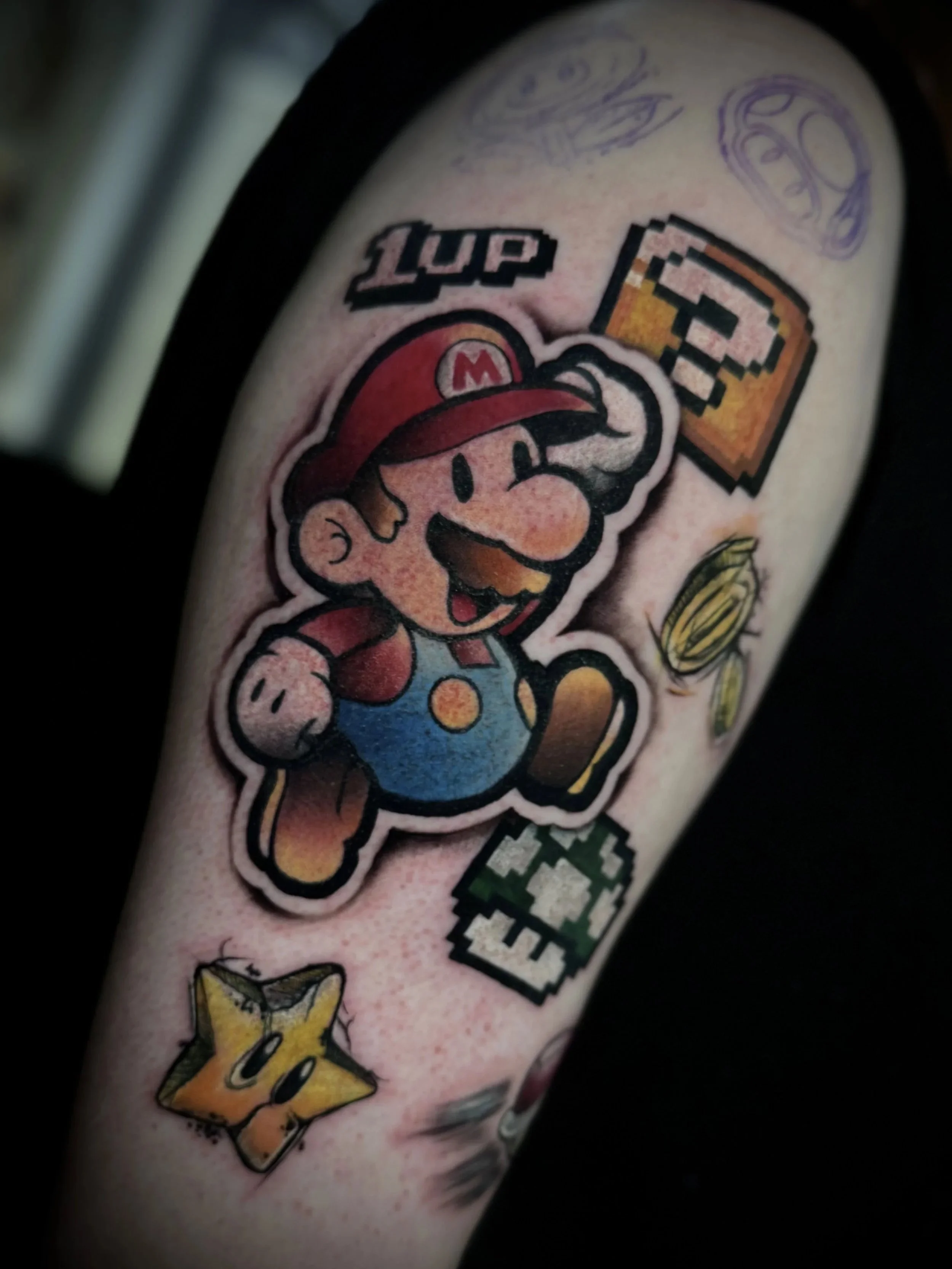 Tattoo auf dem Arm, das Mario von Nintendo zeigt, mit Texten und pixeligen Spielerelementen.