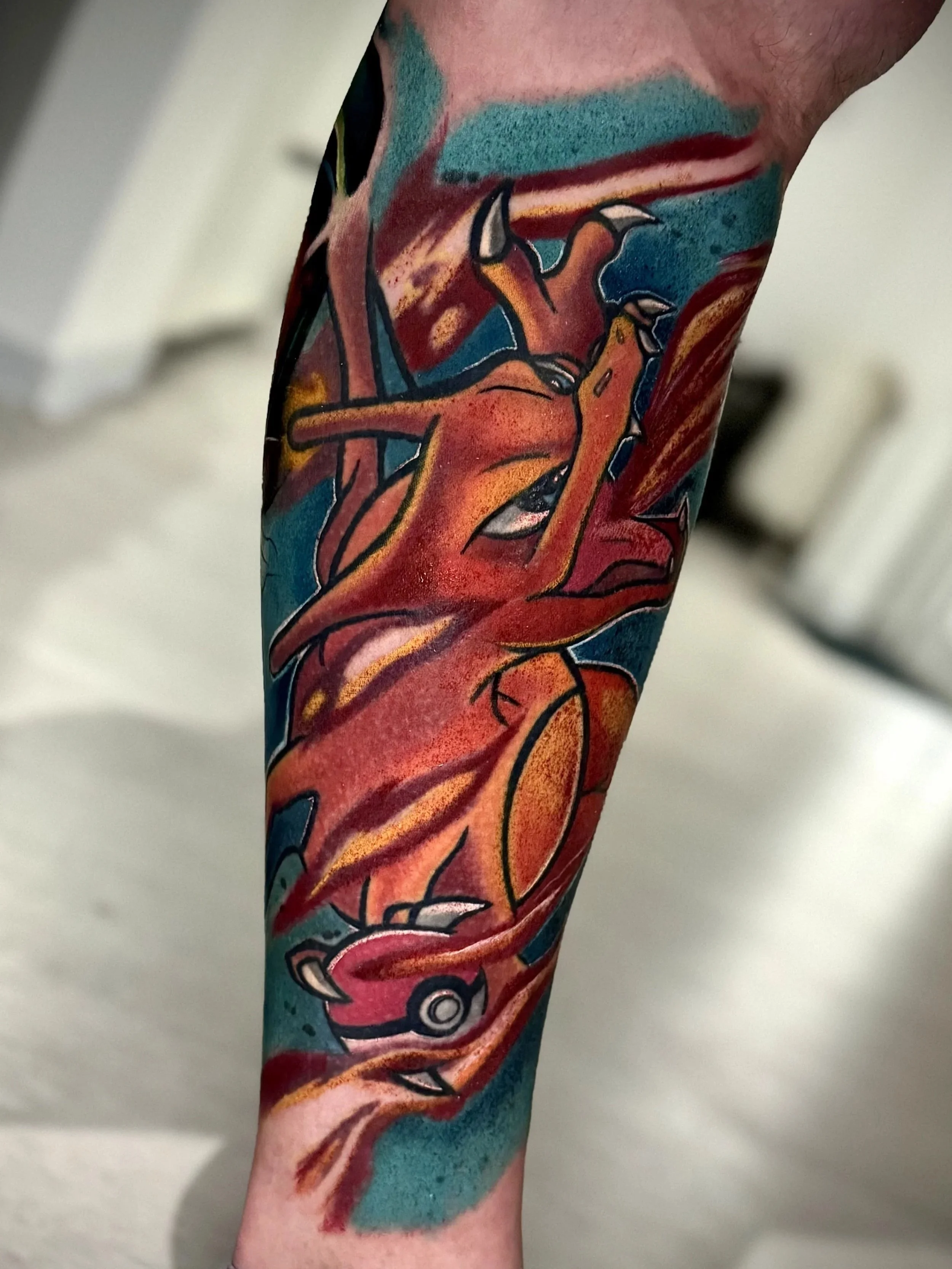 Tattoo eines dämonischen Gesichts auf einem Arm, farbenfrohe kunstvolle Gestaltung mit dunklen Linien und lebendigen Farben.