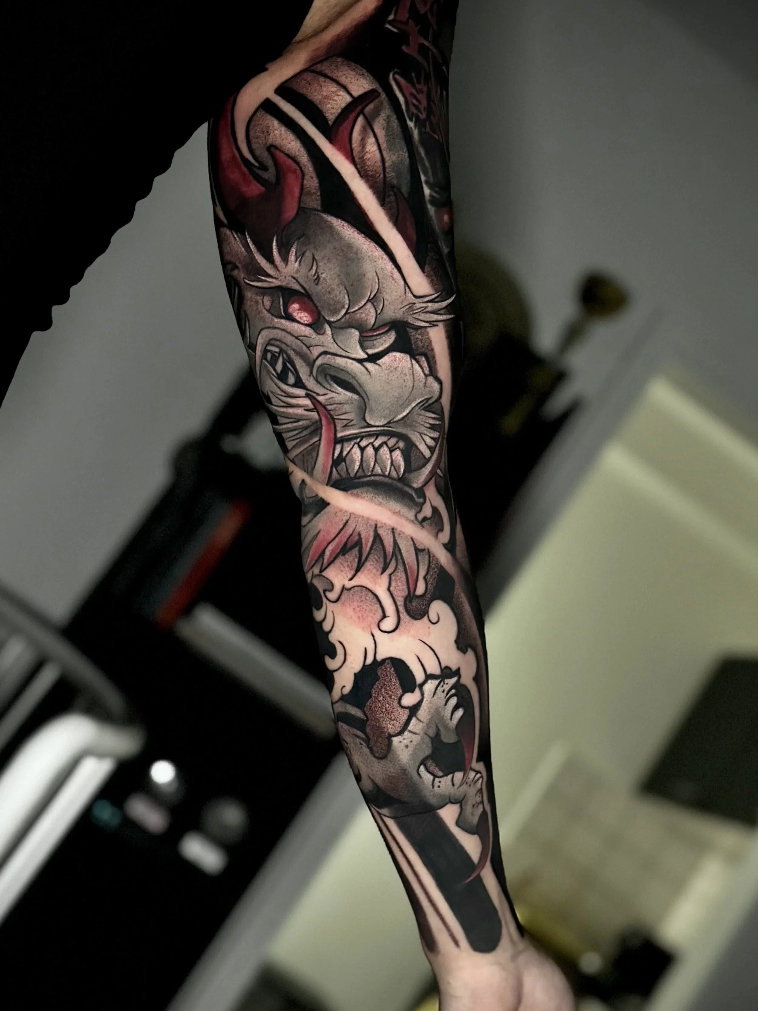 Tattoo eines maskierten Tigers auf dem Arm. Der Arm ist teilweise sichtbar, mit dunklem Hintergrund und einigen technischen Gegenständen im Vordergrund.
