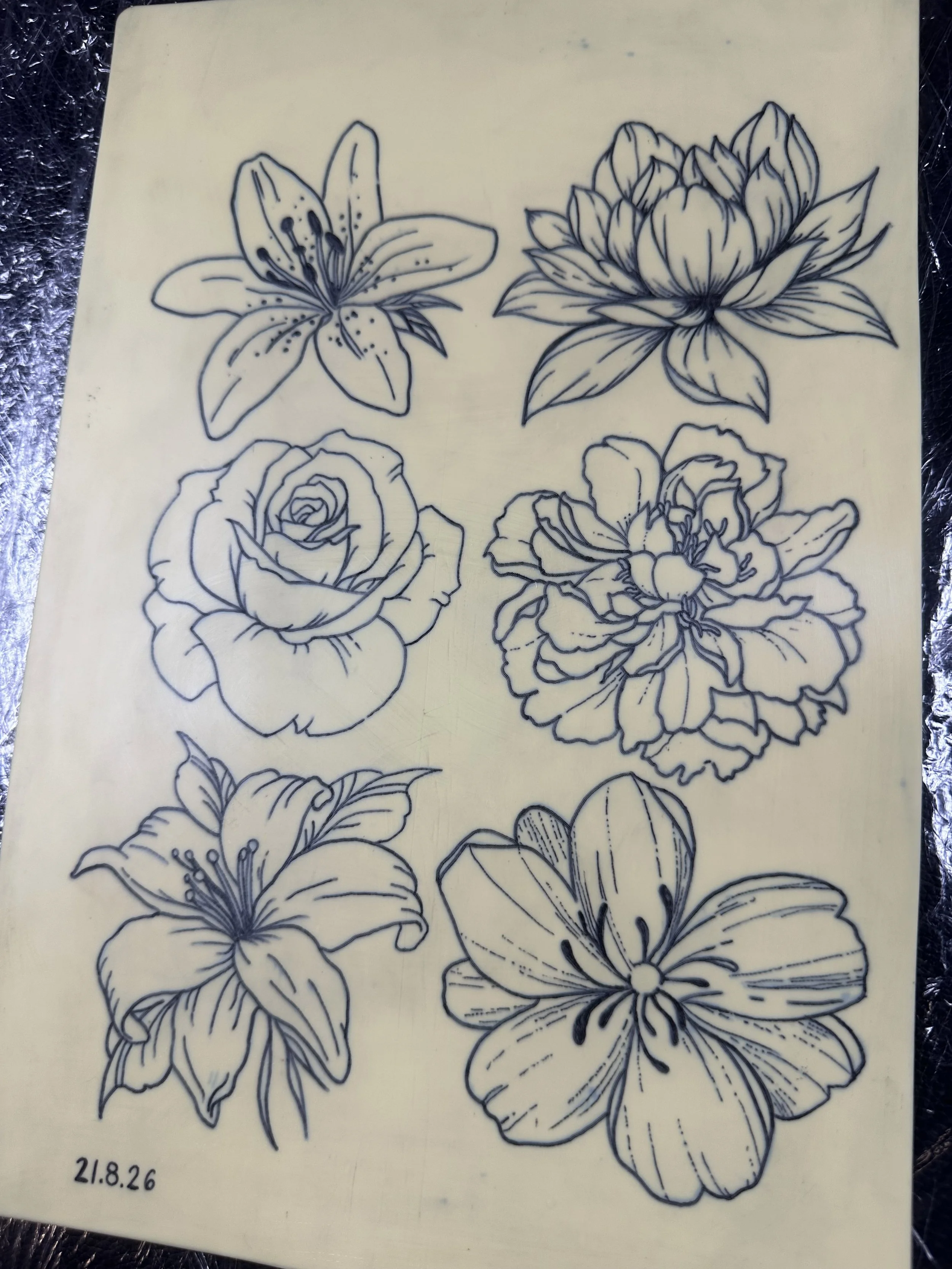 Schwarz-weiße Zeichnungen verschiedener Blumen, darunter Lilien, Rosen, Hibiskus und andere, auf einer hellen Oberfläche.