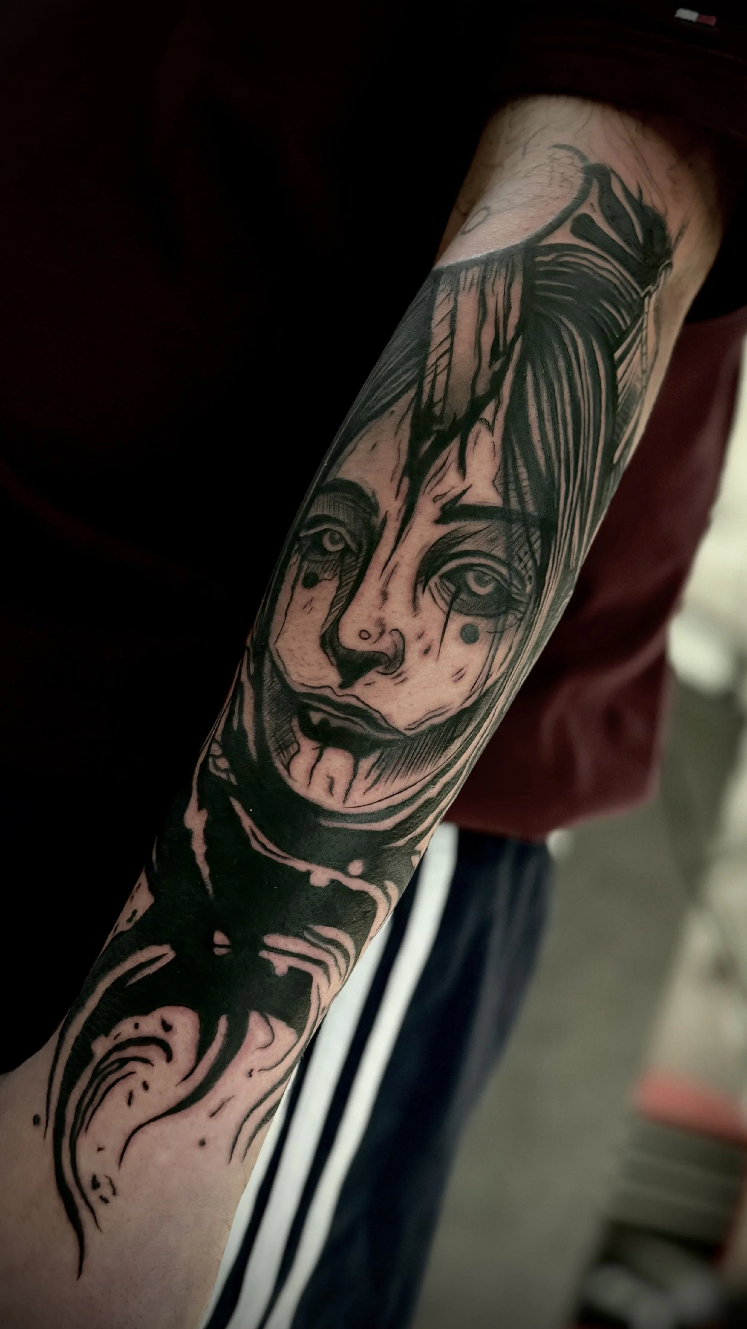 Tattoo eines gesichtsausdrucks mit traurigen oder schmerzverzerrten Merkmalen auf dem Unterarm eines Menschen, Schwarzweiß-Tattoo-Kunst.