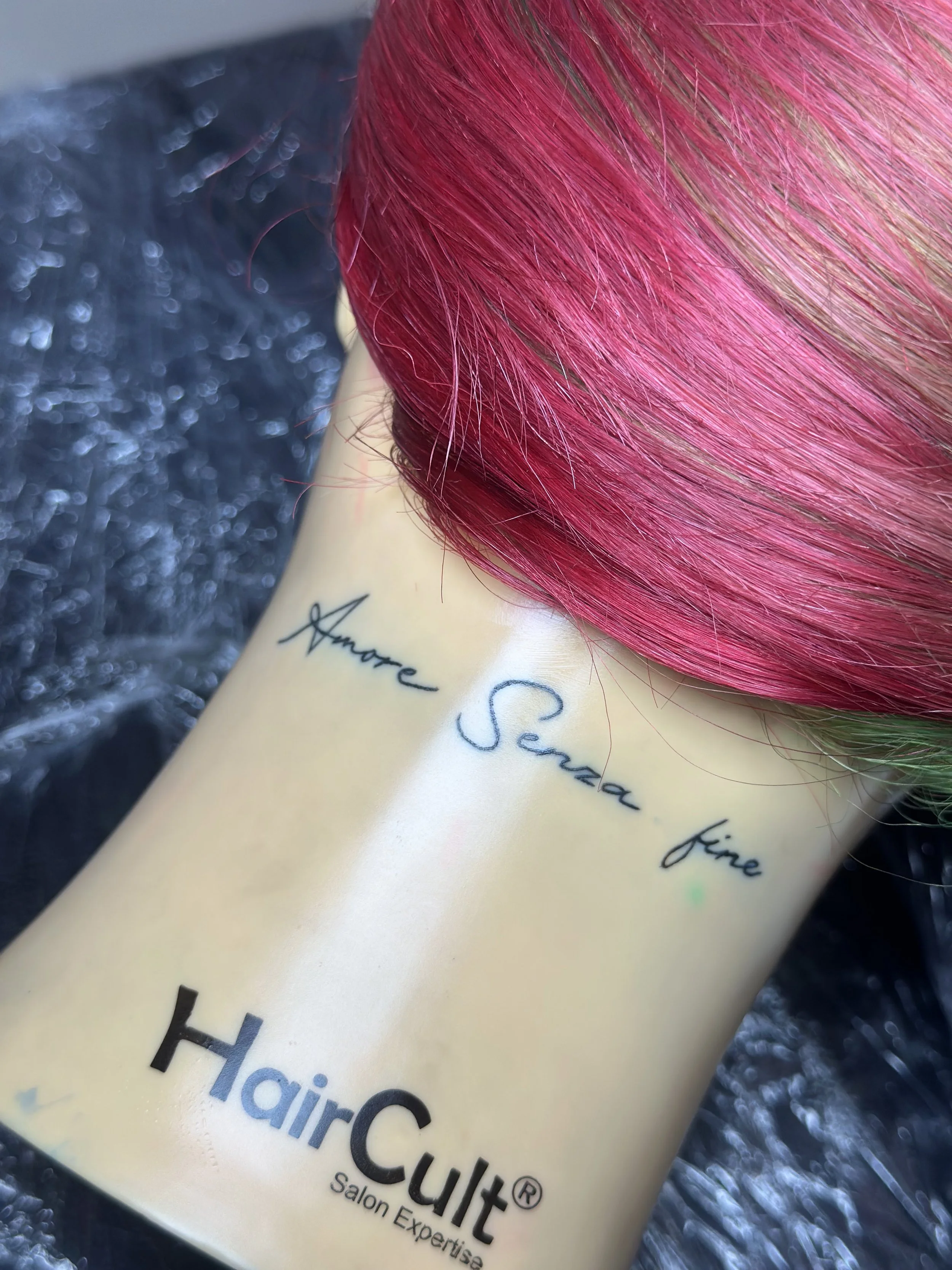 Nahaufnahme einer cremefarbenen Verpackung mit schwarzer Beschriftung, die pink gefärbtes Haar zeigt. Das Produkt ist das HairCouture Salon Exquise.