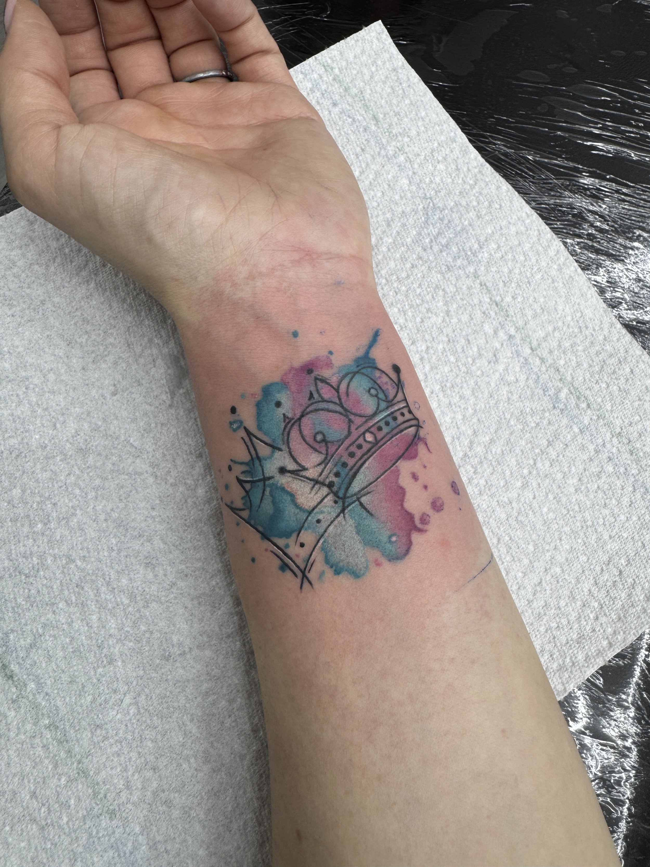Hand mit Tattoo im Wasser und Papierhandtuch neben