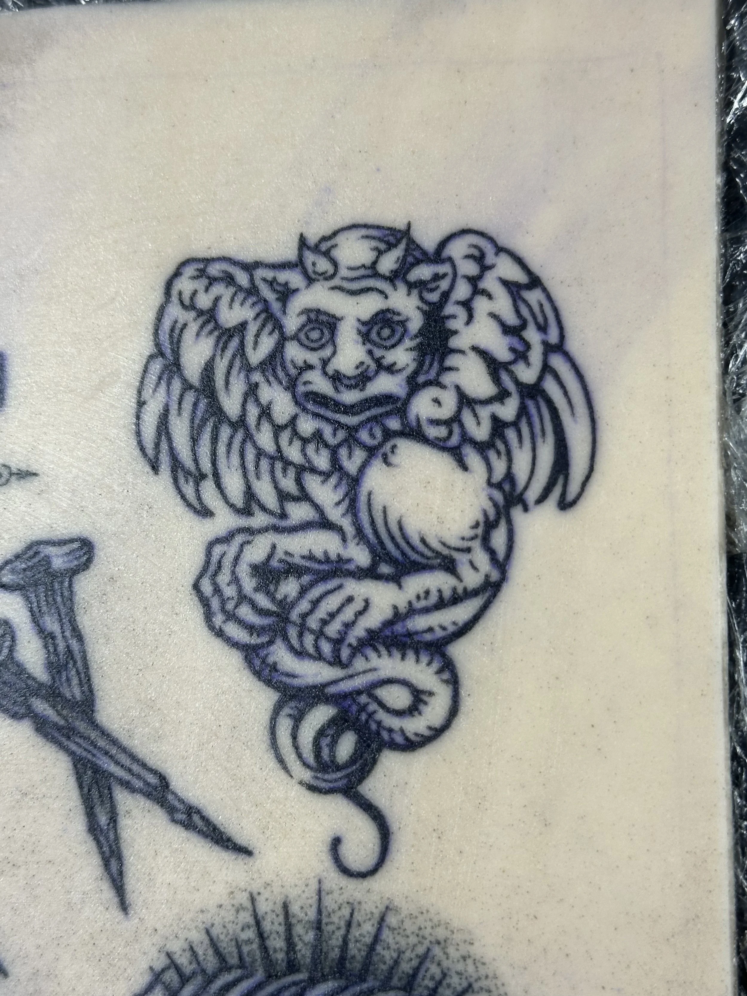 Tattoo eines Sphinx-Kopfes mit Flügeln auf der Haut.