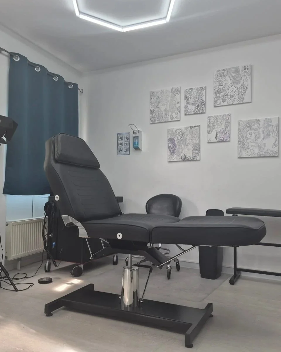 Ein Behandlungsstuhl in einem medizinischen Raum, umgeben von Stühlen, Kunstwerken an der Wand und technischem Equipment.