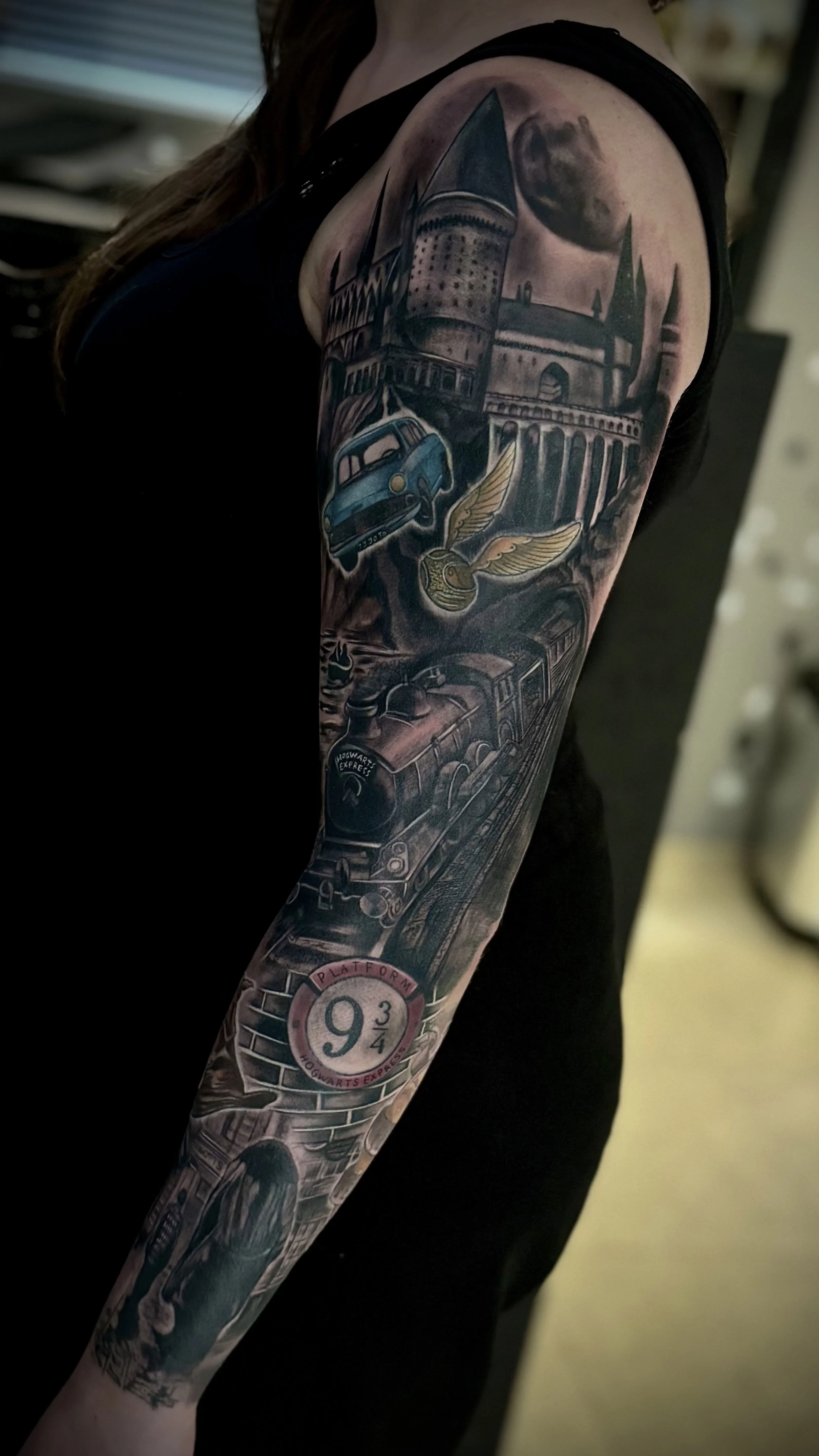 Tattoo eines Hogwarts-Express-Zugs, berühmte Brücke, Mond und Flugzeuge, mit dem nummerischen Zeichen 9 3/4 und dem Schriftzug 'Hogwarts Express'.