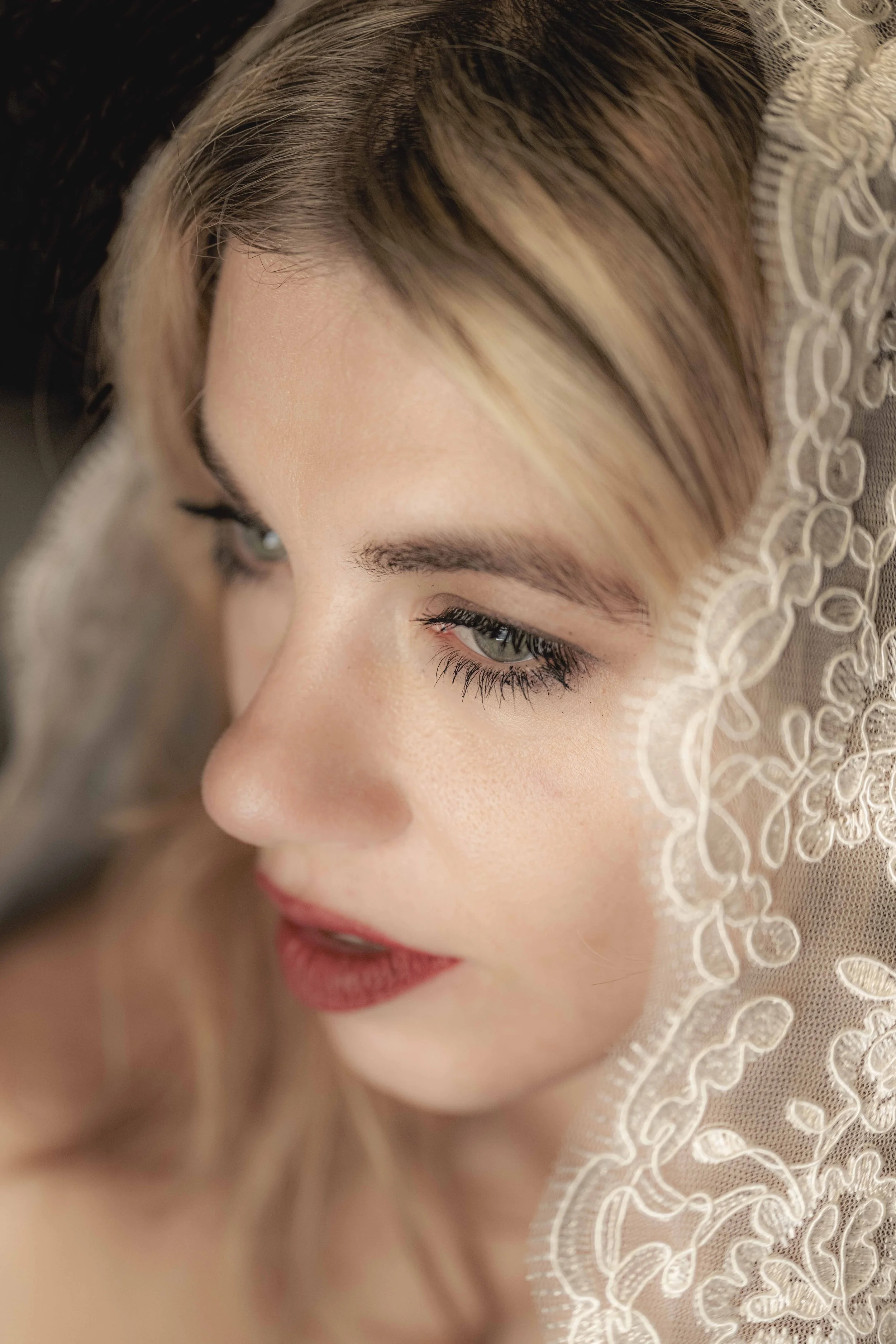Close-up van een vrouw met make-up, gedeeltelijk bedekt met een kanten sluier.