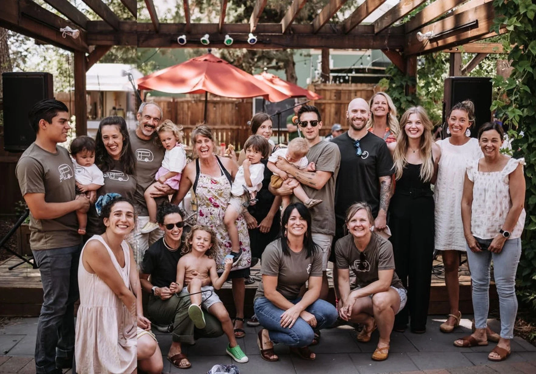 A group photo of Open Door staff smiling for the camera. They're outside in a courtyard, with a wooden stage and trellis in the background.