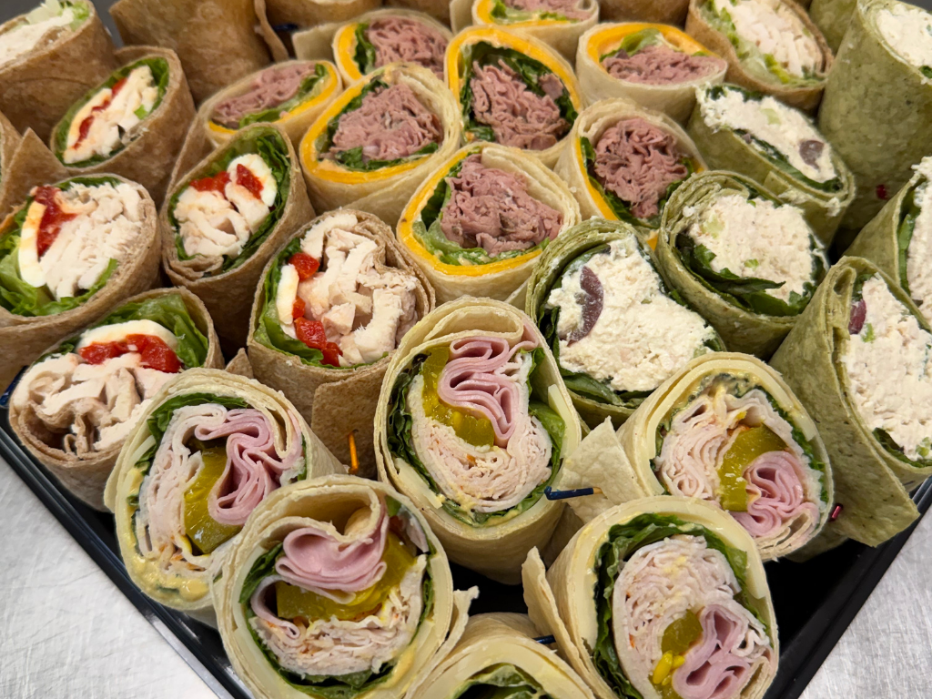 Catering tray with assorted wraps with various meats, cheeses, and vegetables.