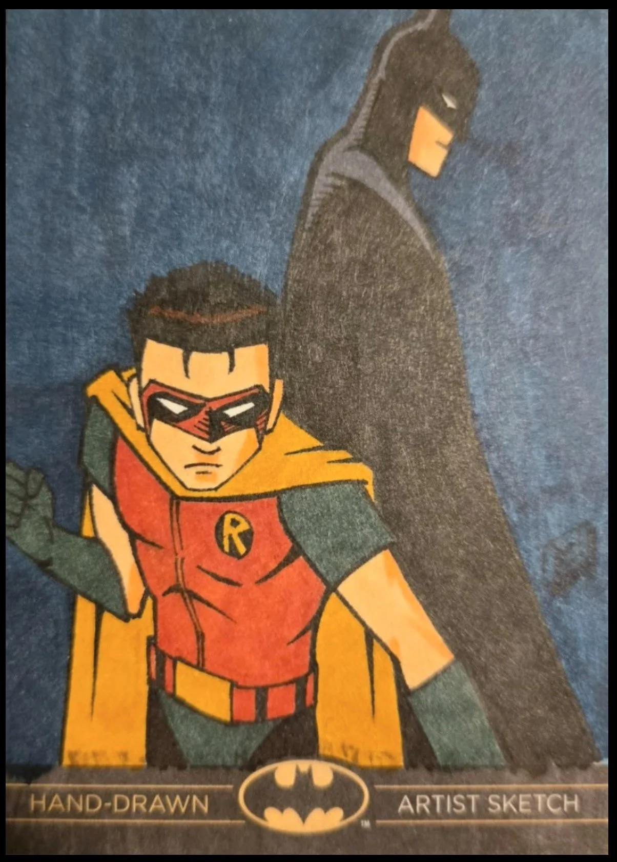Batman legend sketch card. Hand-drawn Batman and Robin comic-style illustration with Bat-Signal, Batman in black cape and Robin in red and green costume, both looking serious against a dark background.