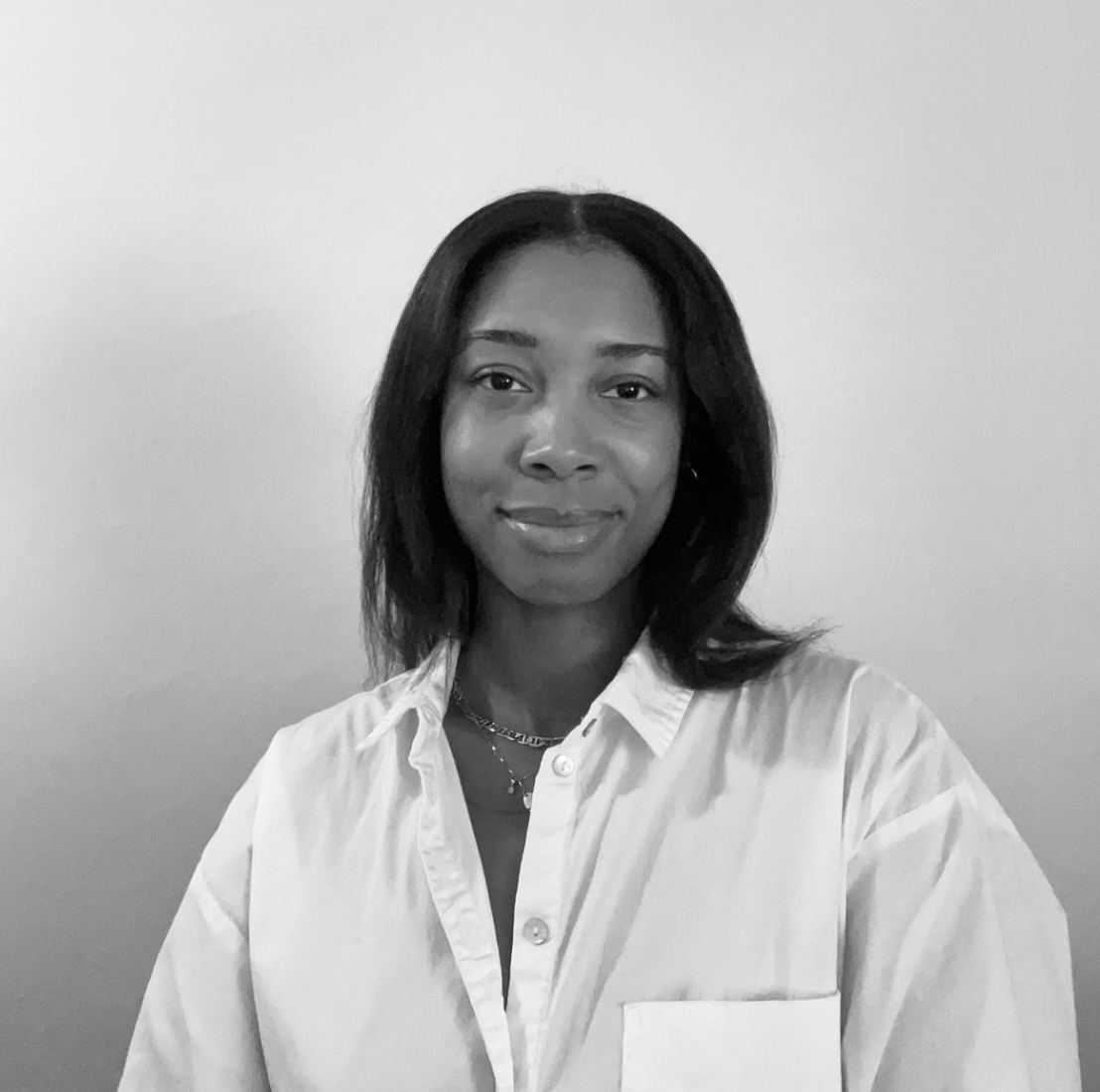 Portrait of a woman with shoulder-length dark hair wearing a white button-up shirt against a plain background.