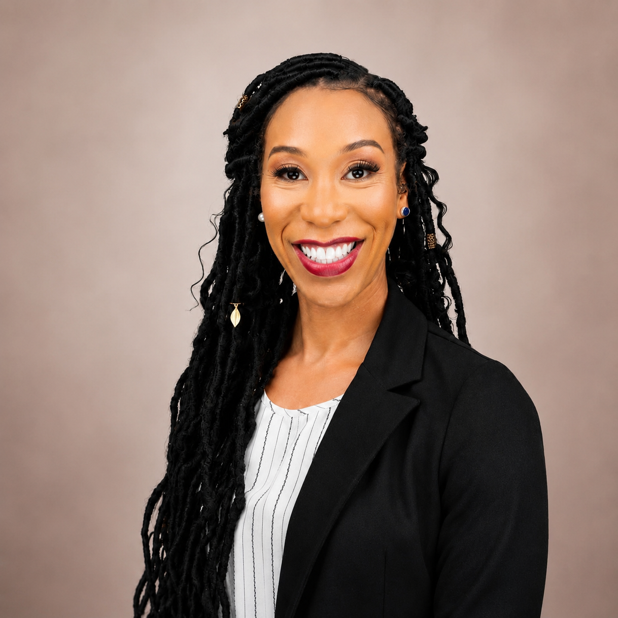 A professional woman with long black braided hair, wearing a black blazer and white striped blouse, smiling against a neutral background.