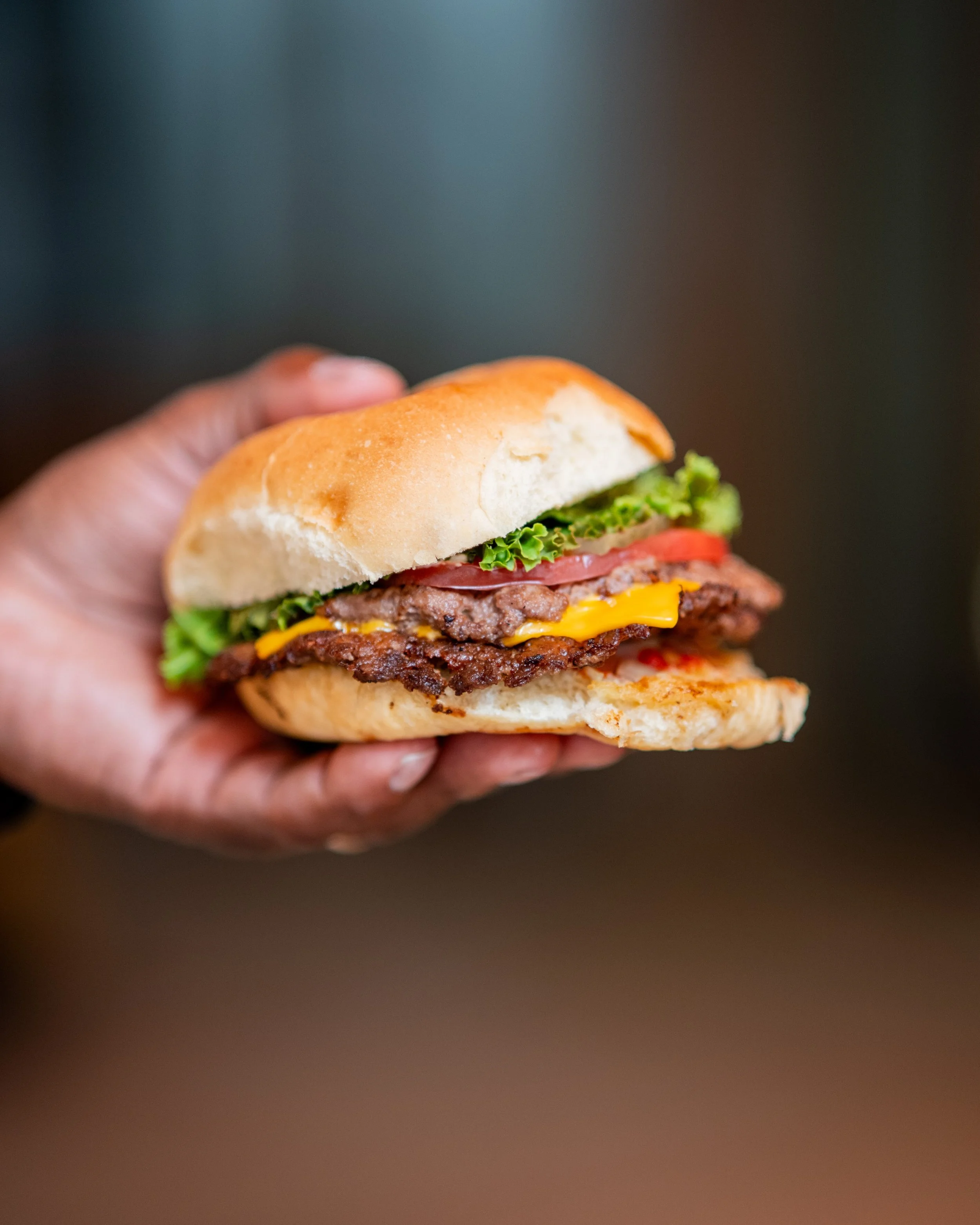 A picture of Smash Burger topped with lettuce, cheese, tomato on a potato bun.