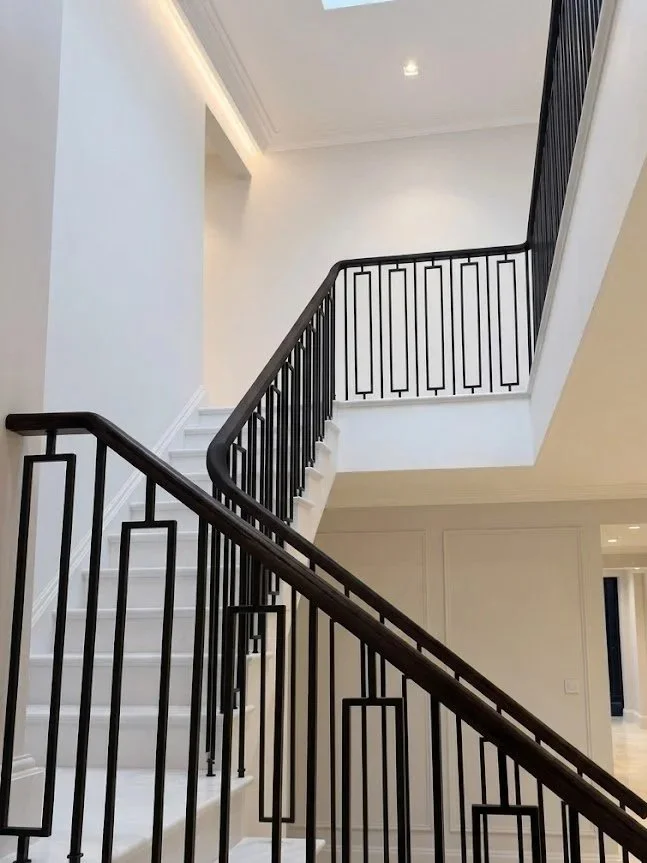 Vertical lightwell view of a multi-flight curved staircase with ebonized black oak handrail and geometric steel balustrades in Welwyn Hertfordshire by Ken Pope Custom Joinery