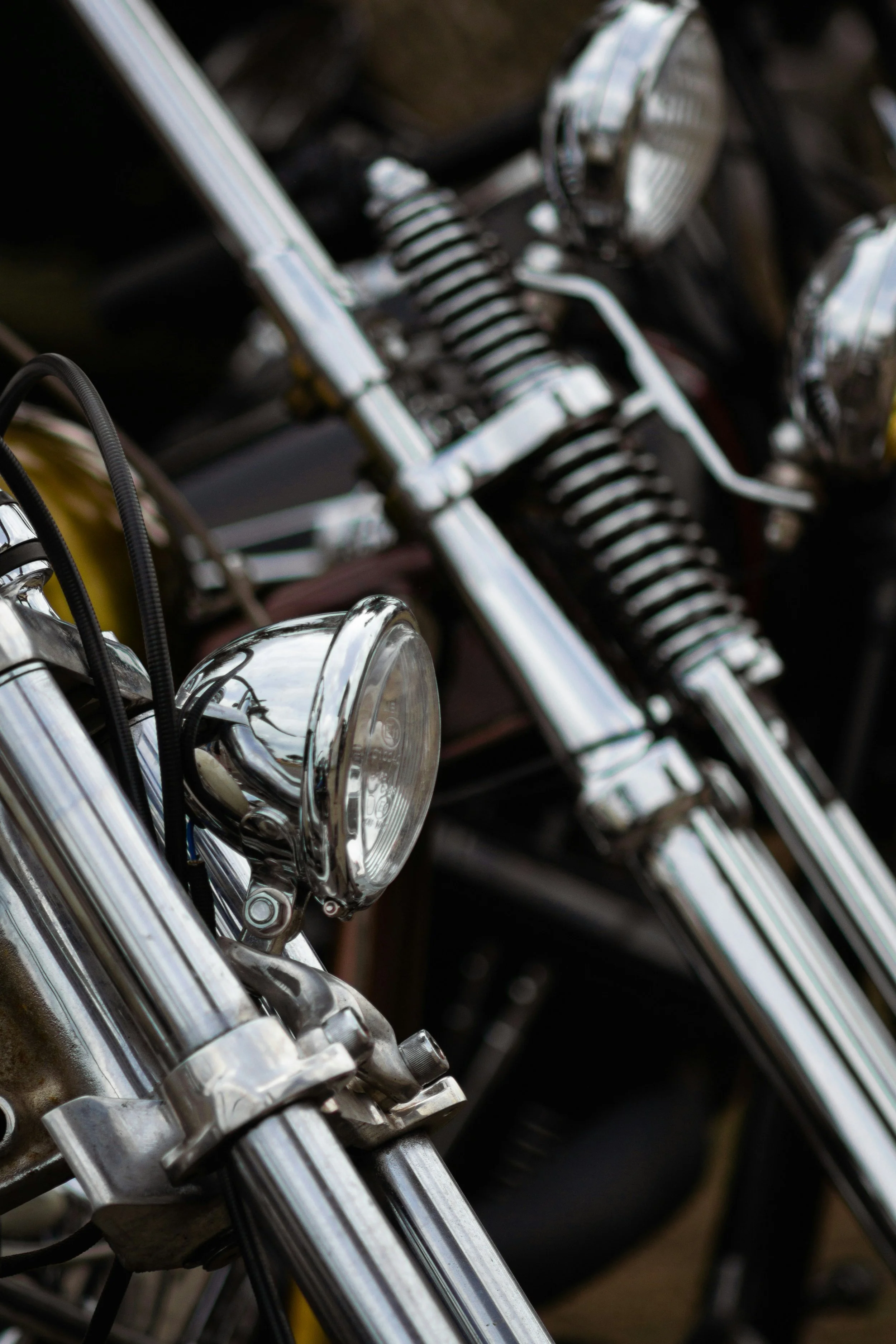 Close-up of chrome motorcycle front forks and headlight.