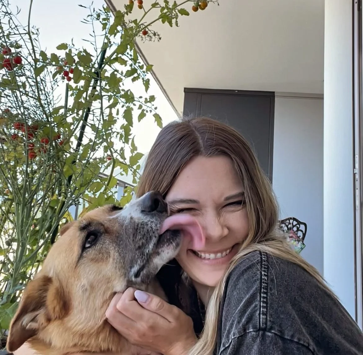 Kaitlyn, owner of The Gentle Shepherd Anesthesia-Free Canine Dental Cleaning, smiling with her dog outdoors.